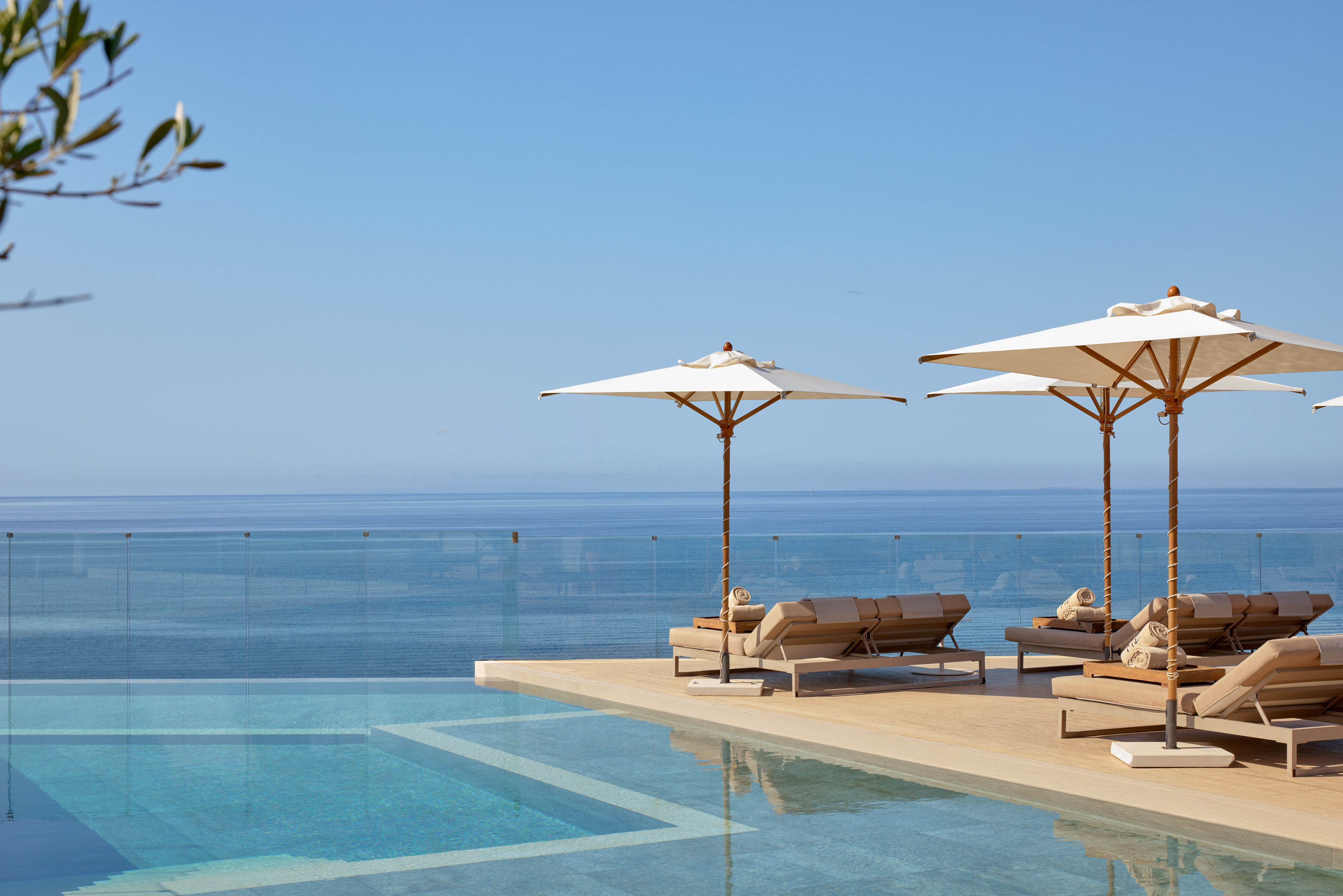 Luxury infinity pool with sun loungers, umbrellas, and ocean view.