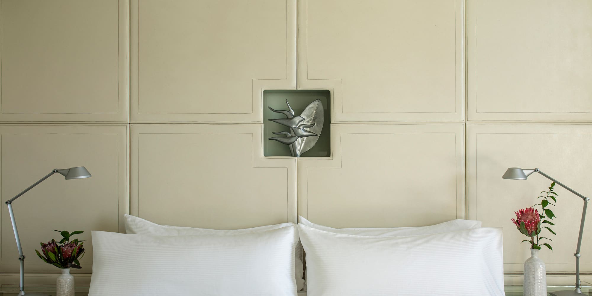 a bed with white pillows and a lamp on the side