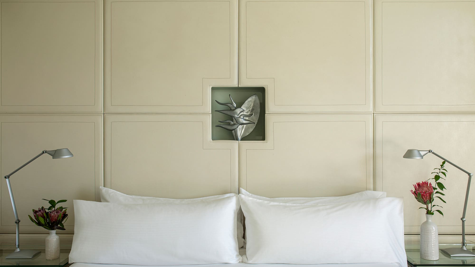 a bed with white pillows and a lamp on the side