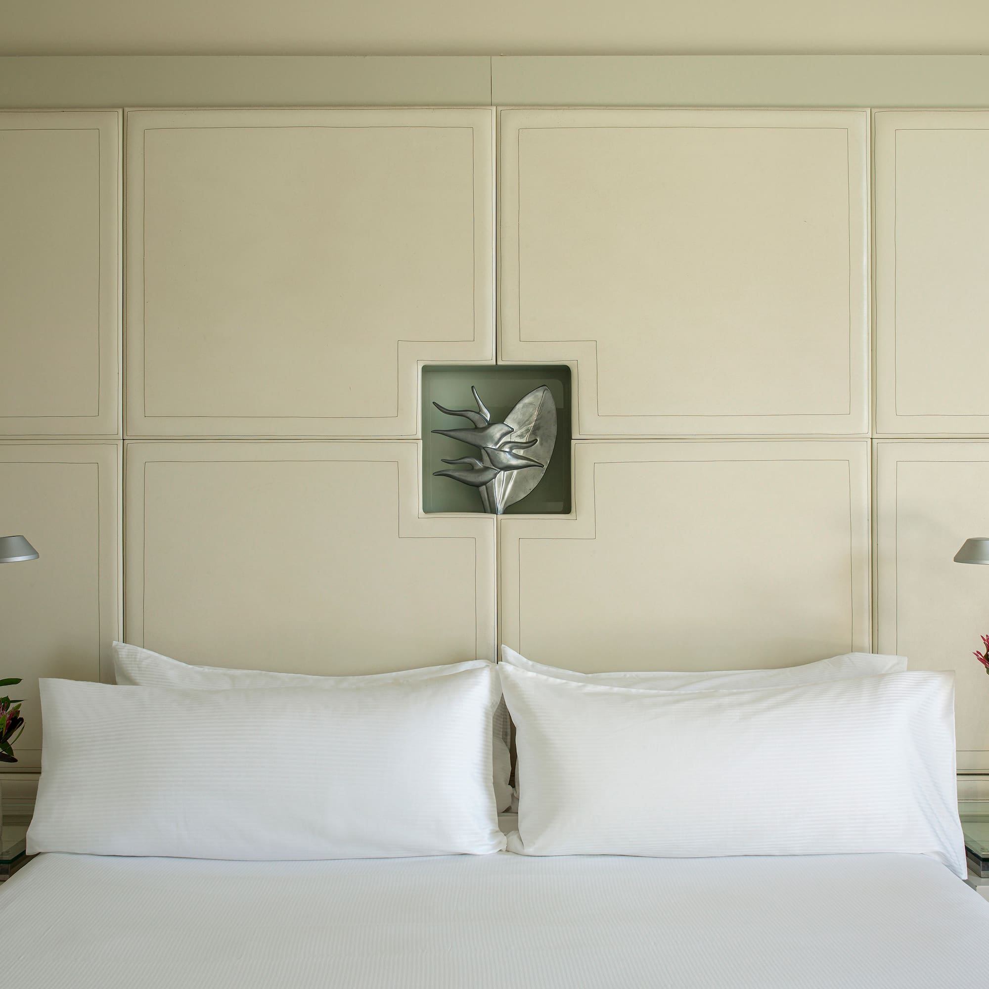 a bed with white pillows and a lamp on the side