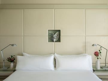 a bed with white pillows and a lamp on the side