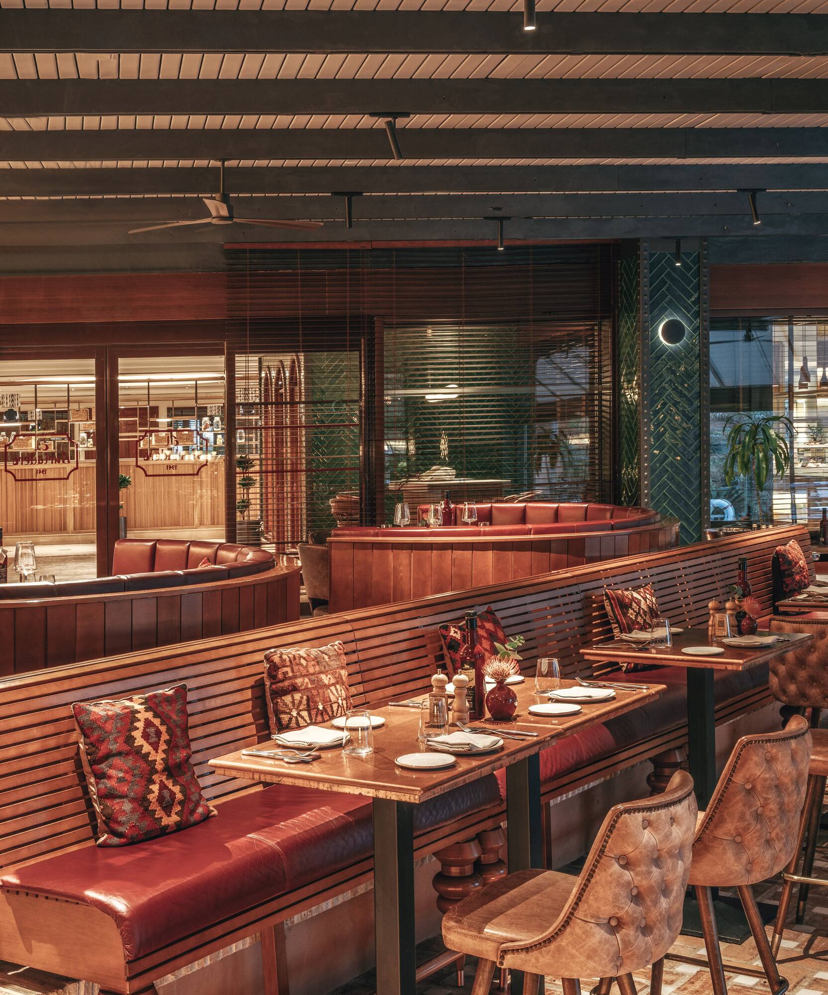 Elegant restaurant interior with red leather booths, dark wood, and set tables.