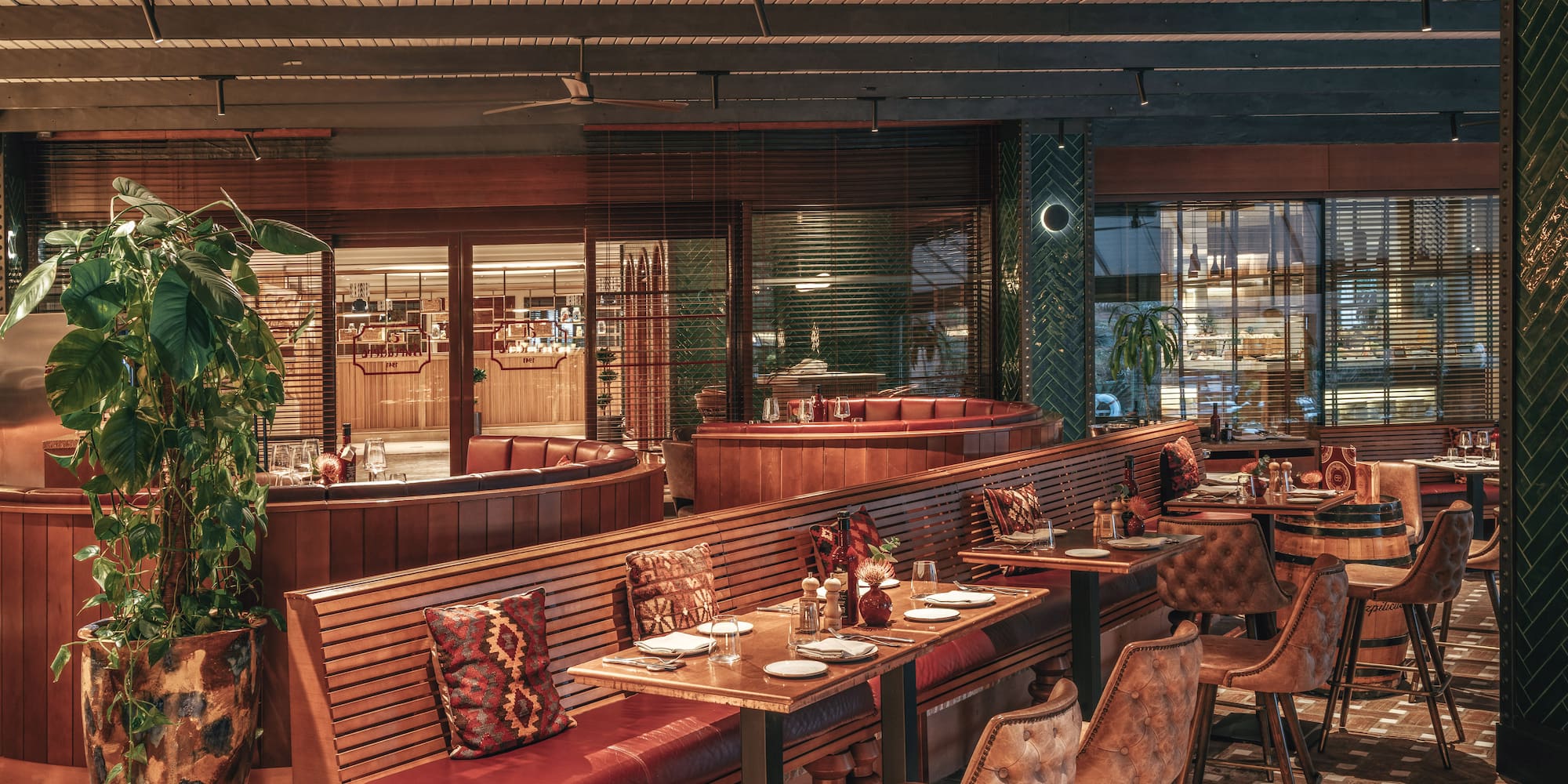 Elegant restaurant interior with red leather booths, wooden tables, and warm lighting.