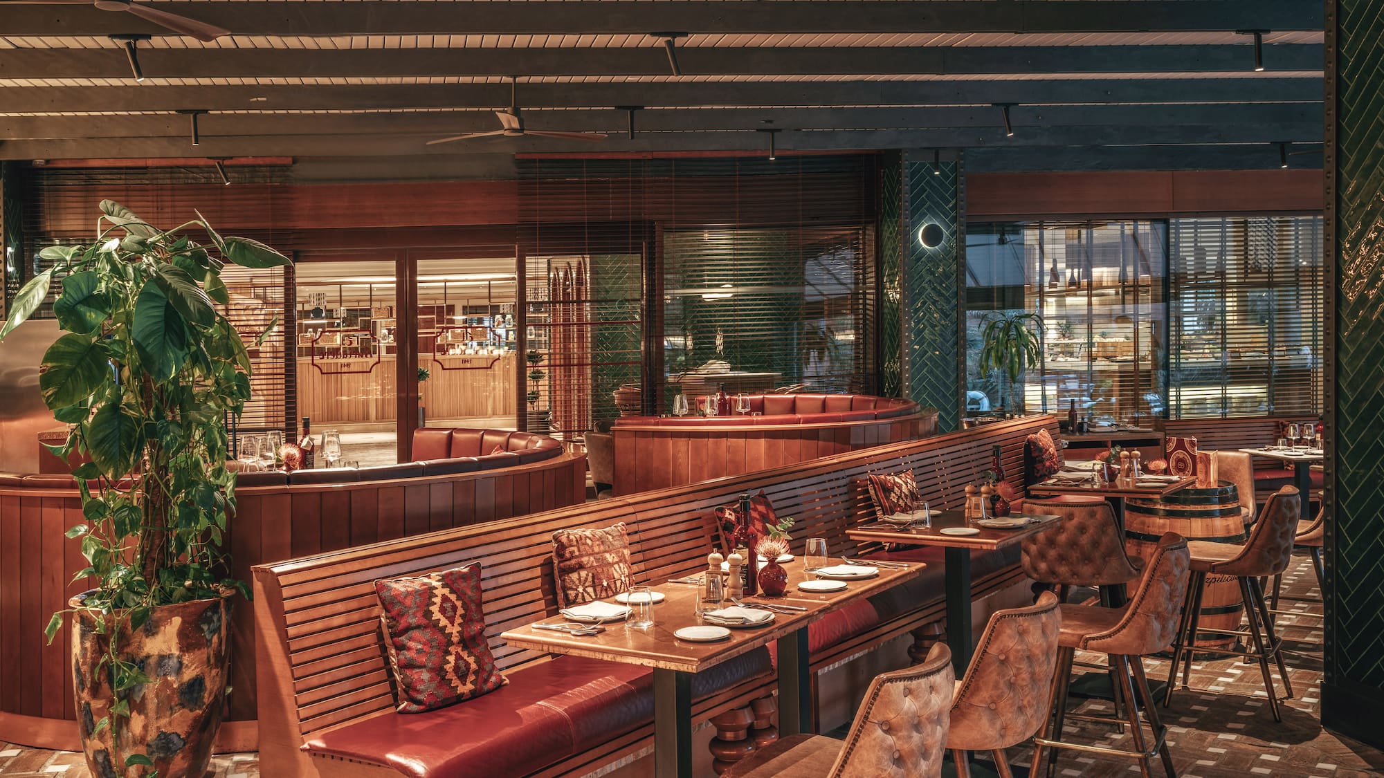 Restaurant dining area with wooden booths, red leather seating, and bar stools.