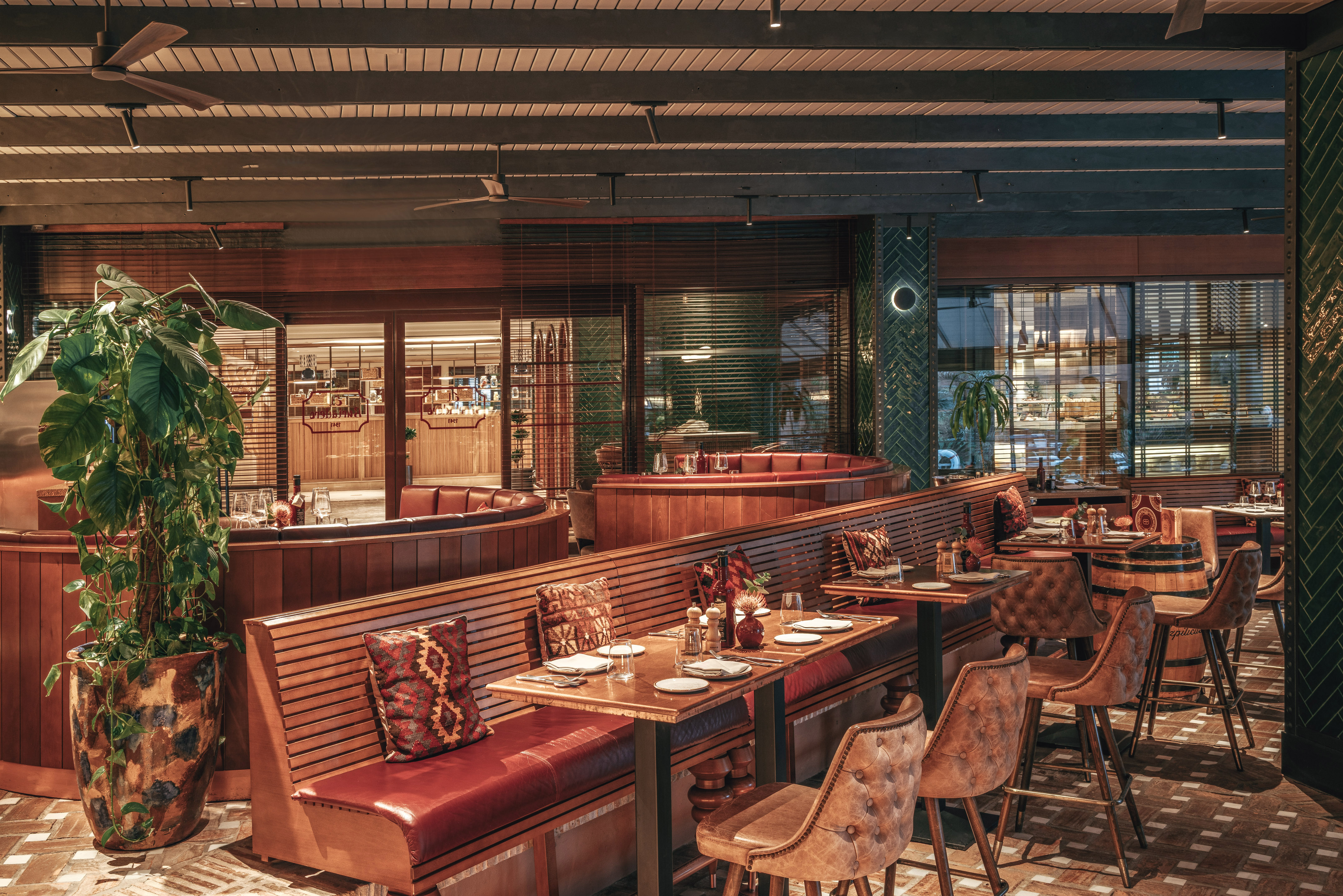 Restaurant dining area with wooden booths, red leather seating, and bar stools.