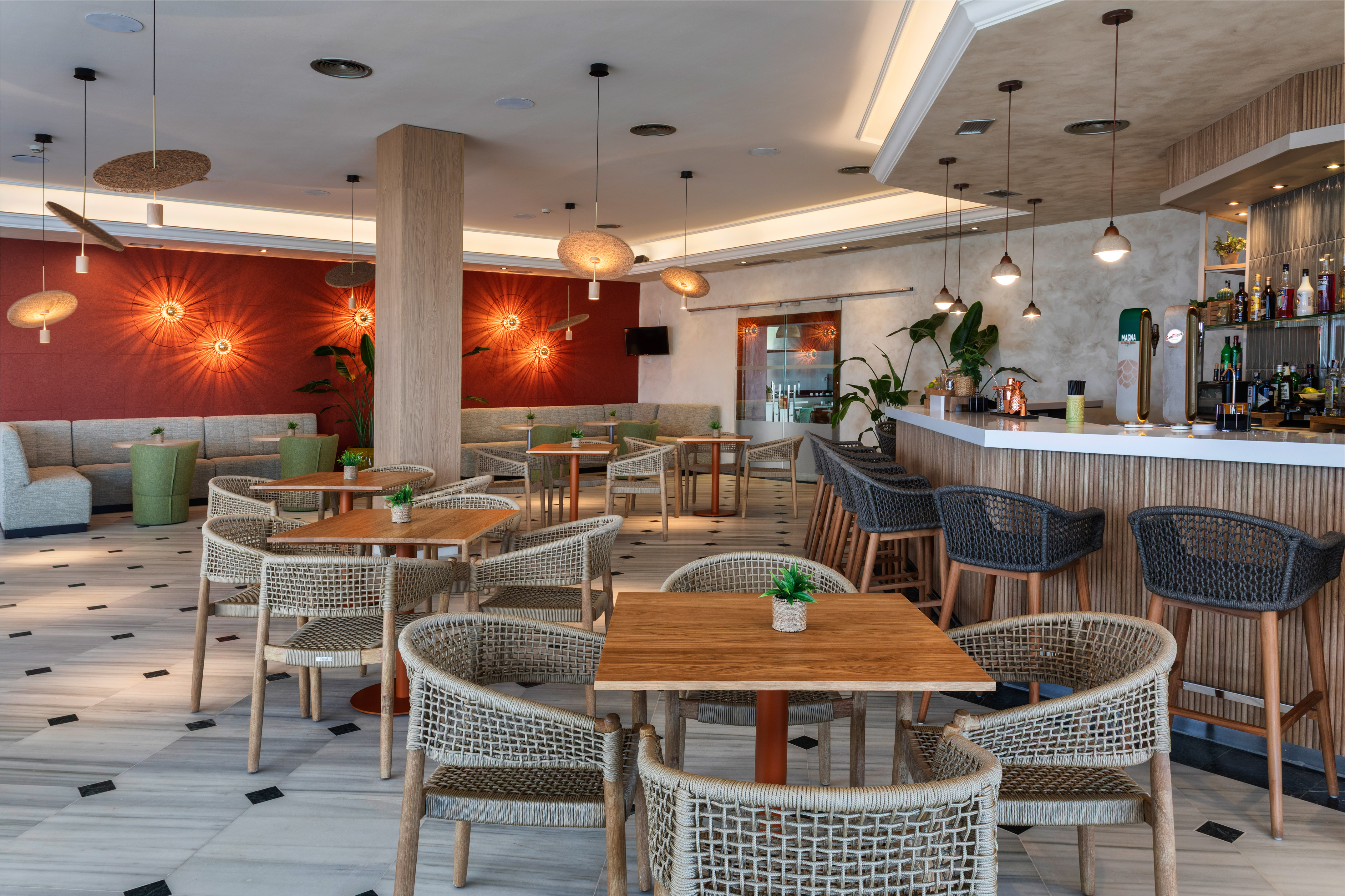 Comedor de hotel moderno con barra, mesas y sillas de mimbre.