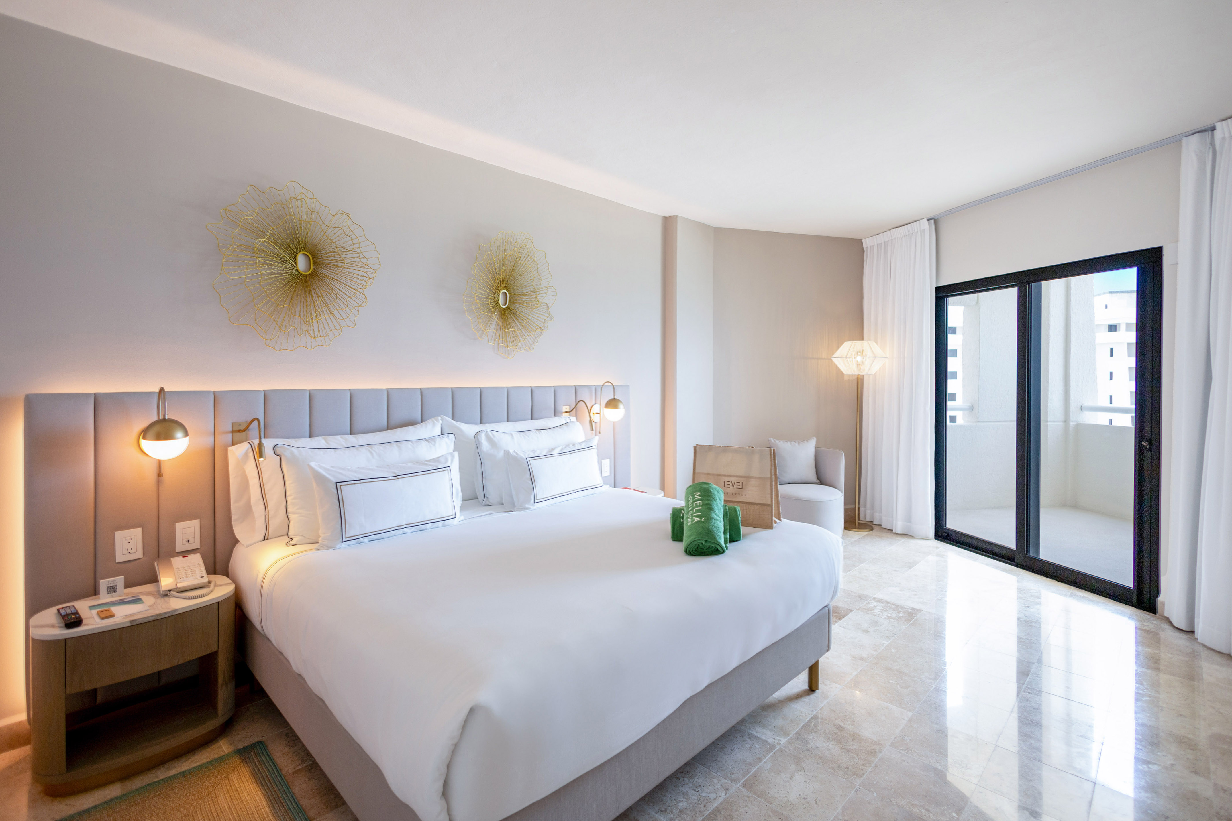 Luxury hotel room with king bed, golden accents, balcony, and tiled floor.