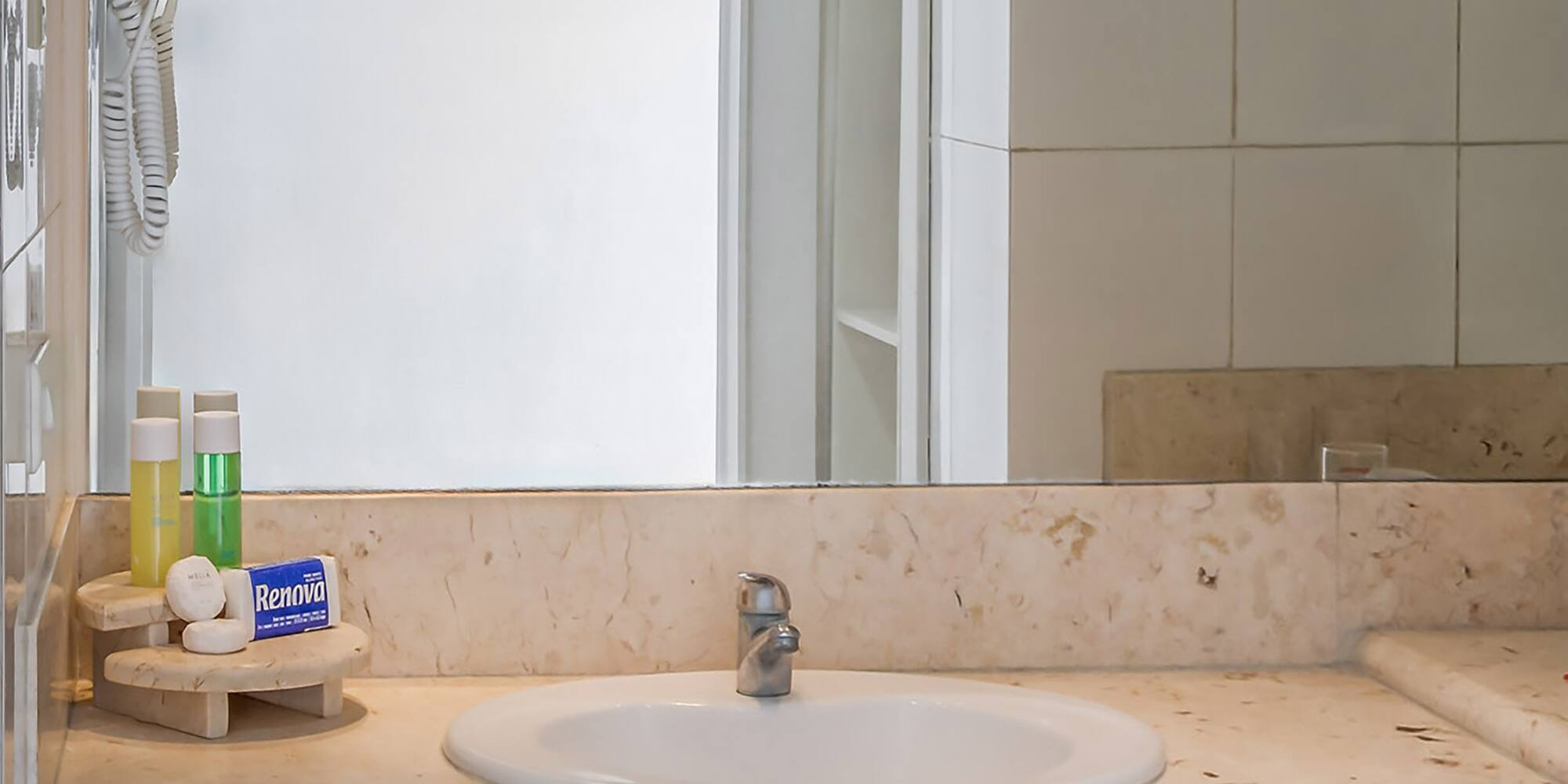a bathroom sink with a mirror and a white tile wall