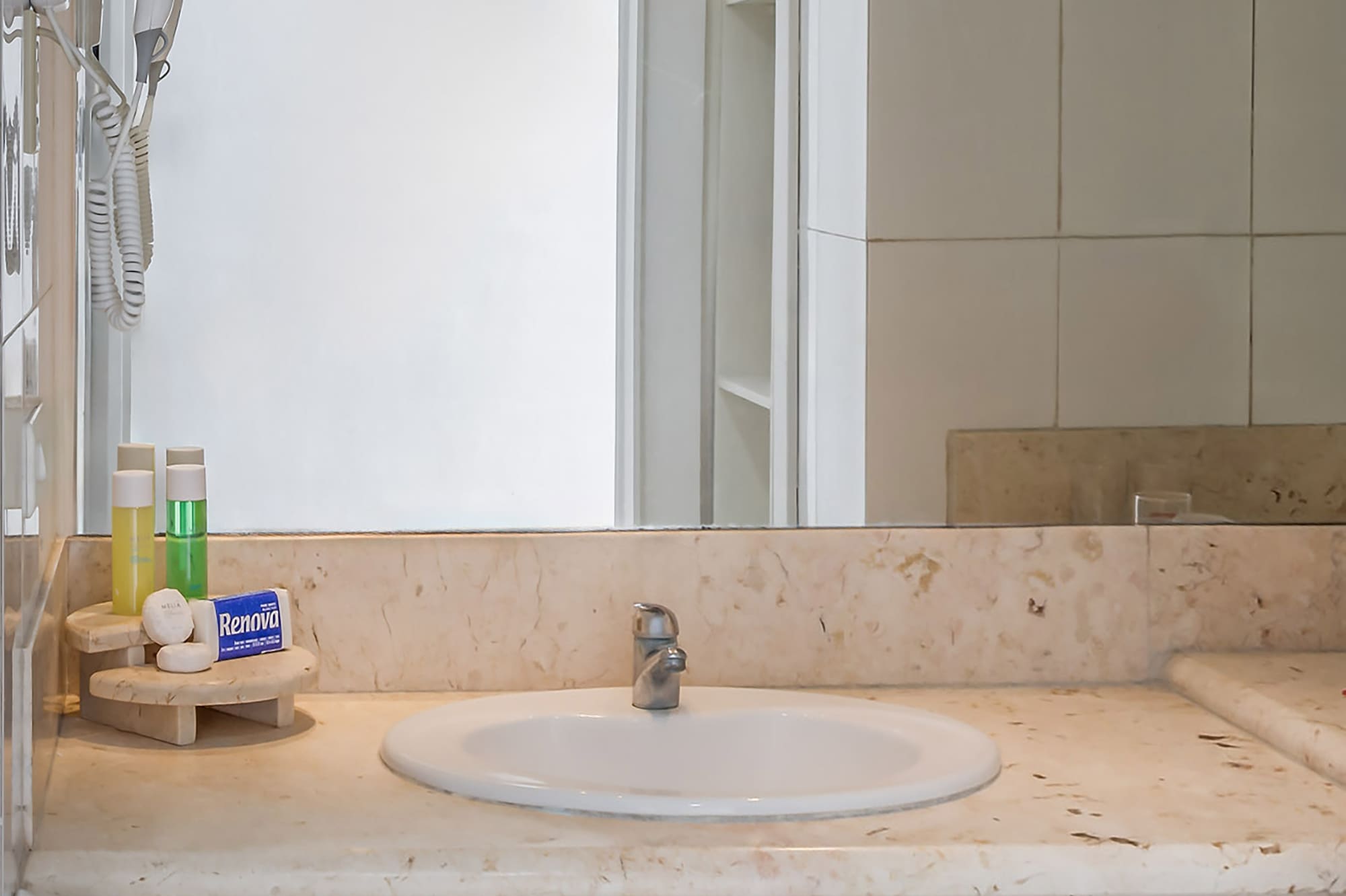 a bathroom sink with a mirror and a white tile wall