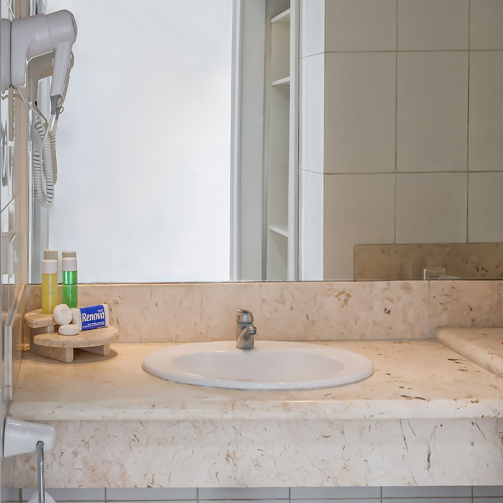 a bathroom sink with a mirror and a white tile wall