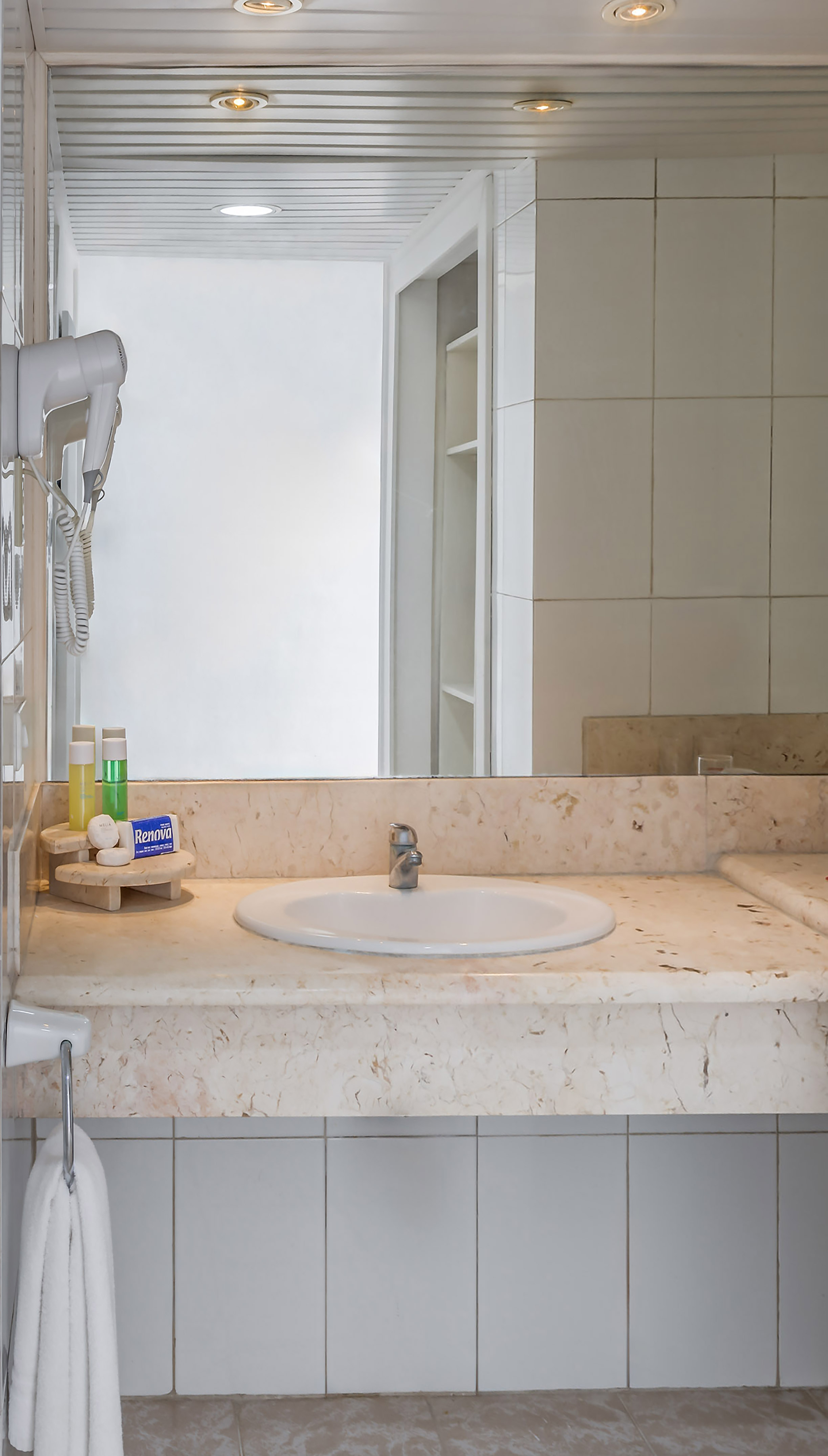 a bathroom sink with a mirror and a white tile wall