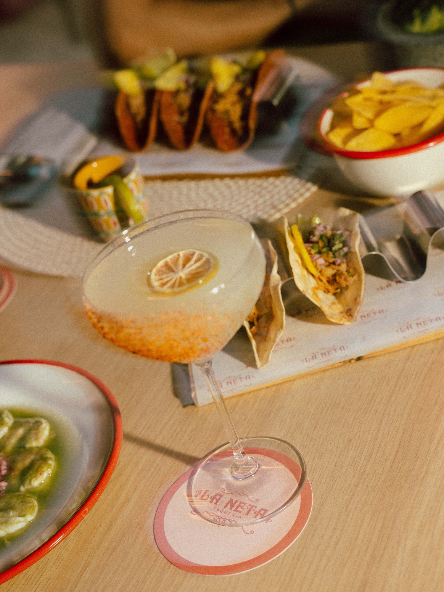 Tacos, citrus cocktail, and chips on a table at La Neta Taqueria.