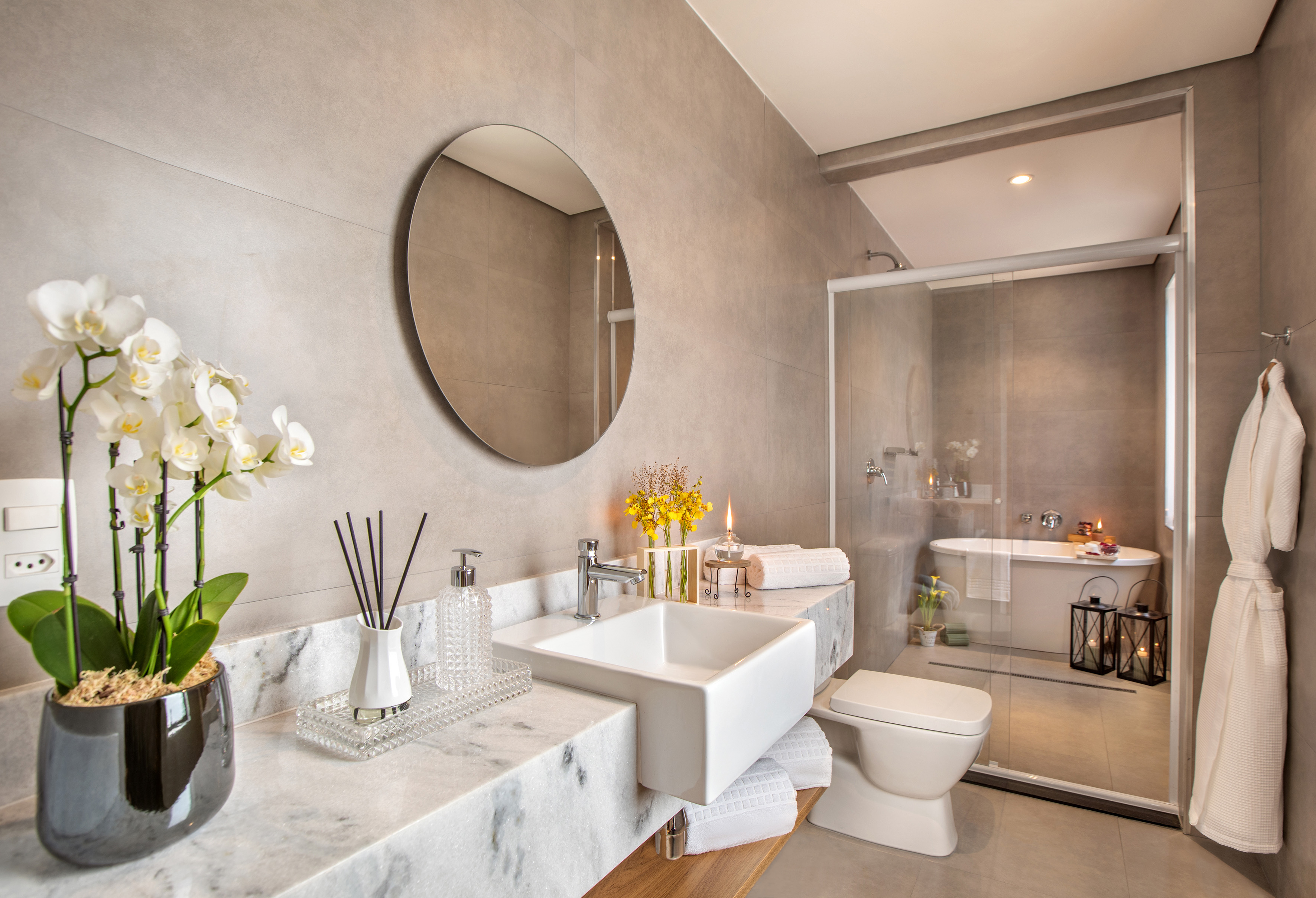 Modern bathroom with marble vanity, vessel sink, white orchids, and bathtub.