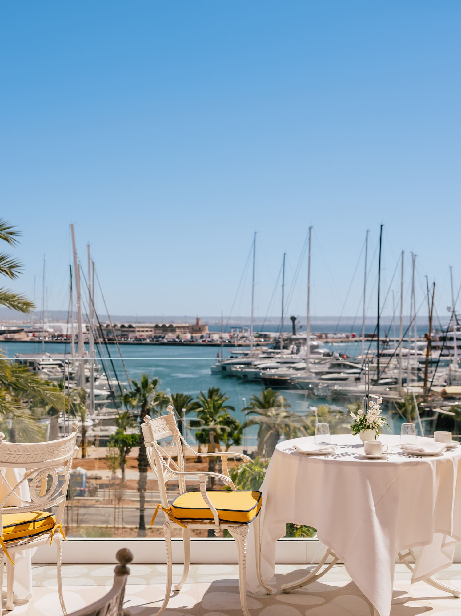 a table and chairs with a view of a marina and boats in the background