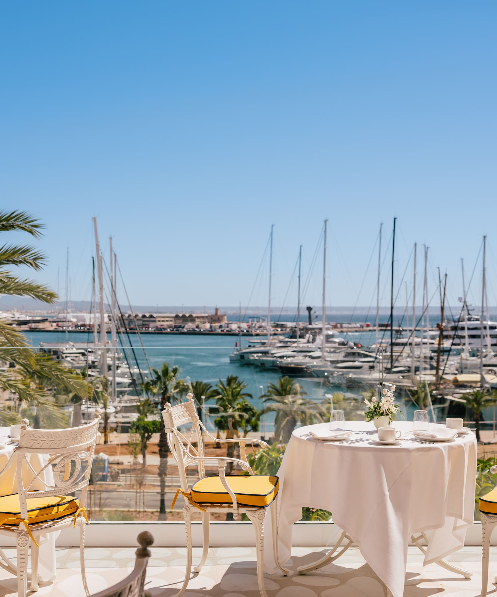 a table and chairs with a view of a marina and boats in the background