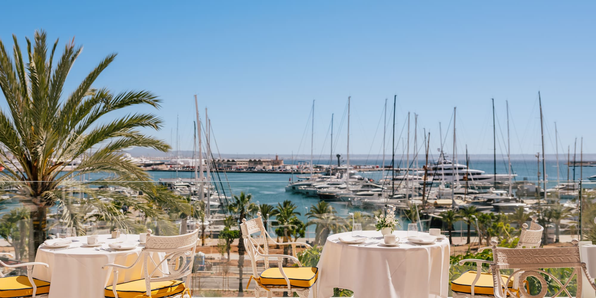 a table and chairs with a view of a marina and boats in the background