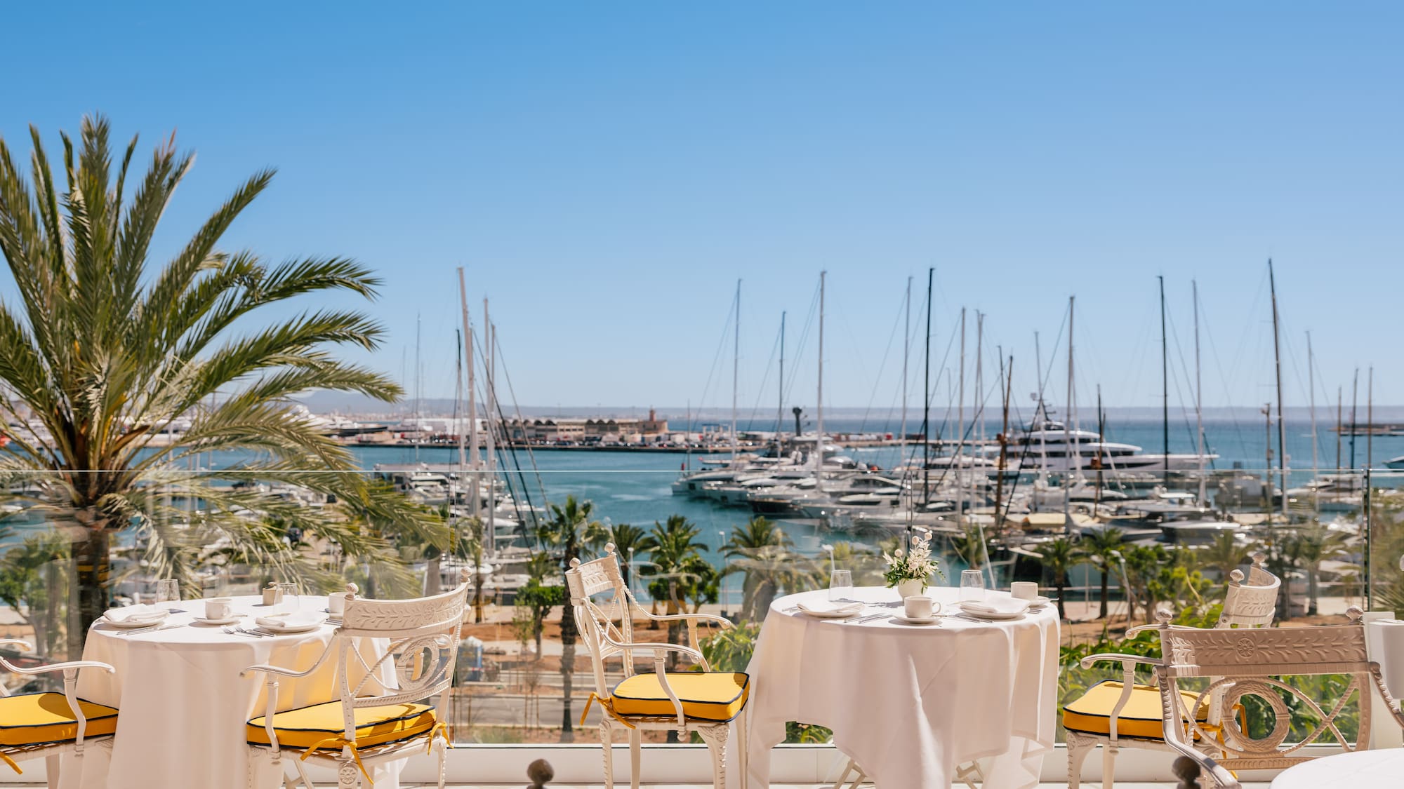 a table and chairs with a view of a marina and boats in the background