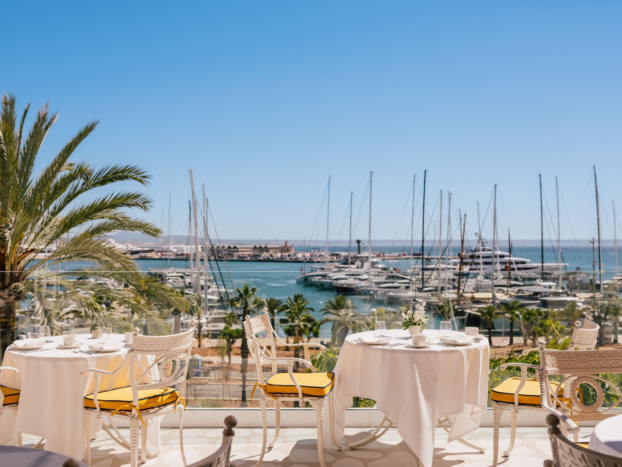 a table and chairs with a view of a marina and boats in the background