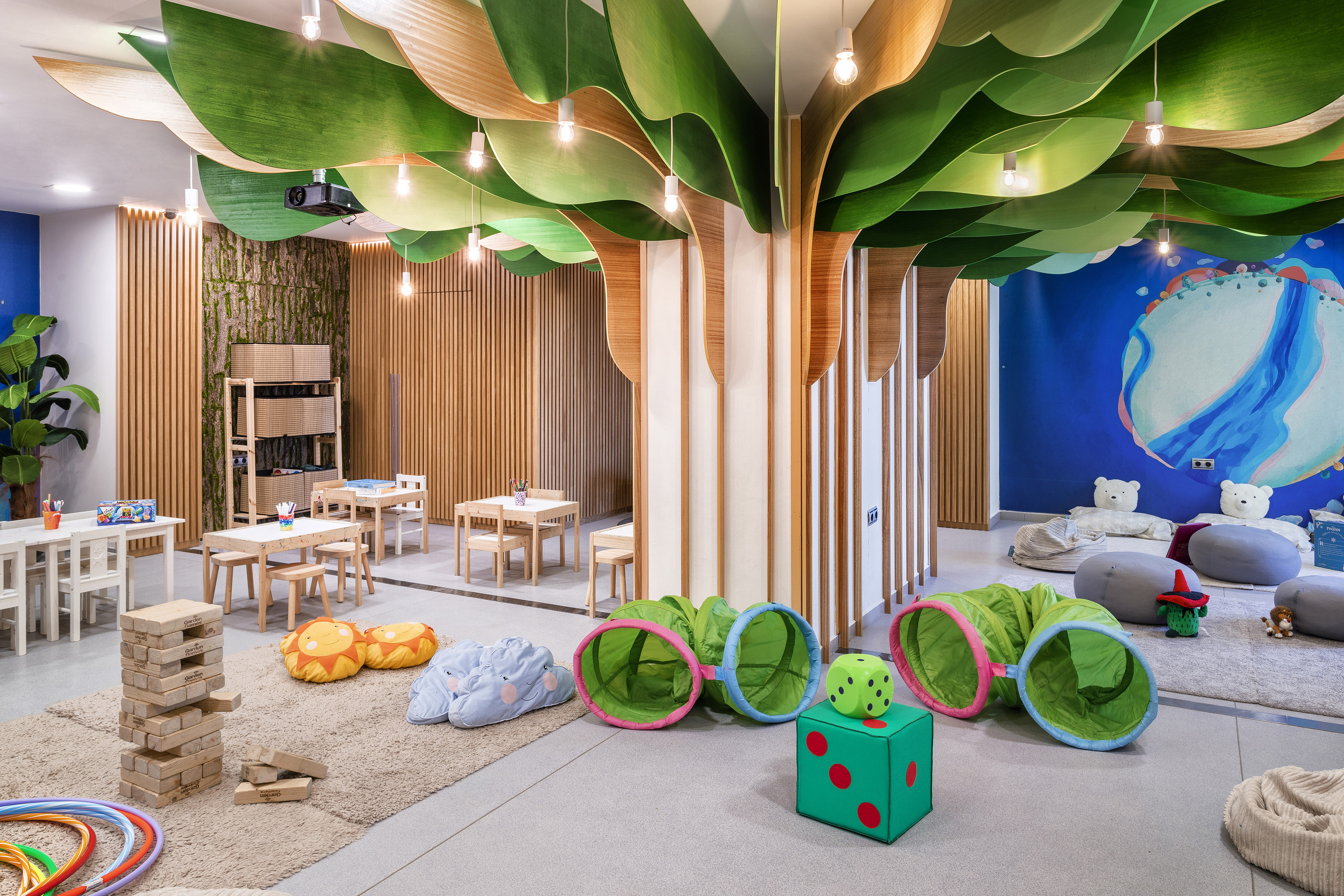 Tree-themed kids' play area with tunnels, small furniture, and nature decor.