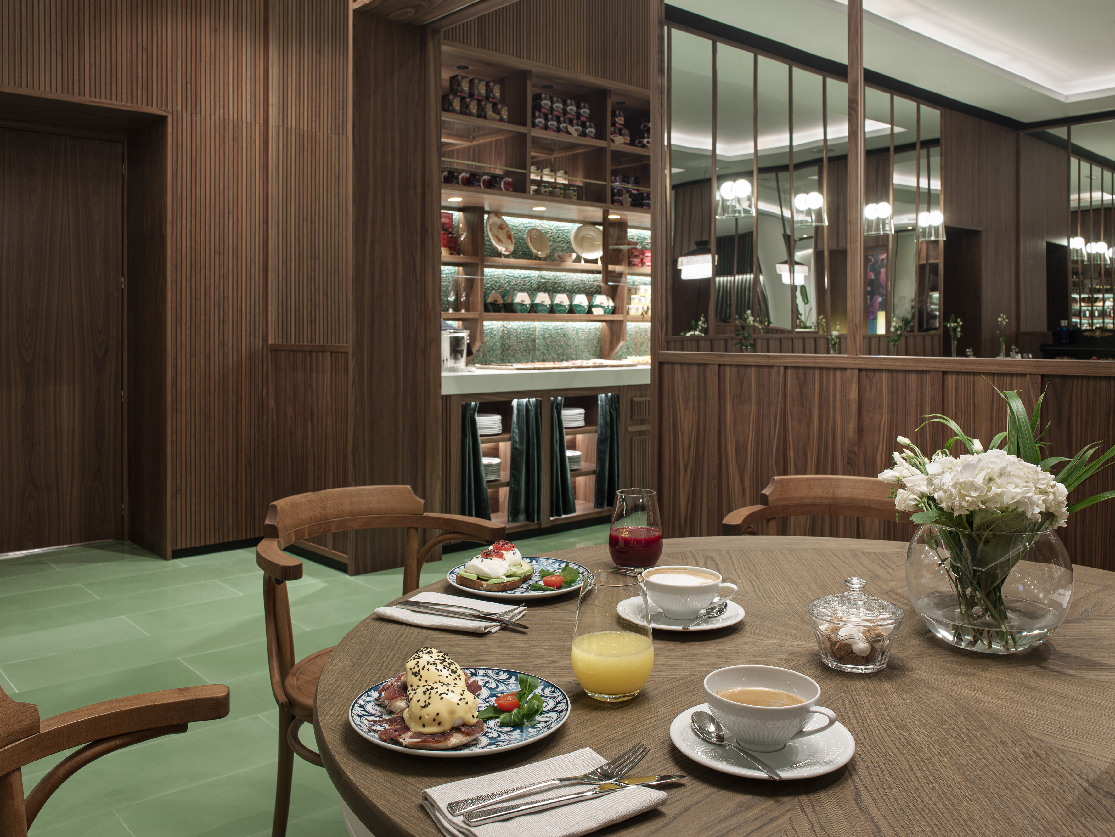 Hotel breakfast: Eggs Benedict, avocado toast, coffee on a wooden table.