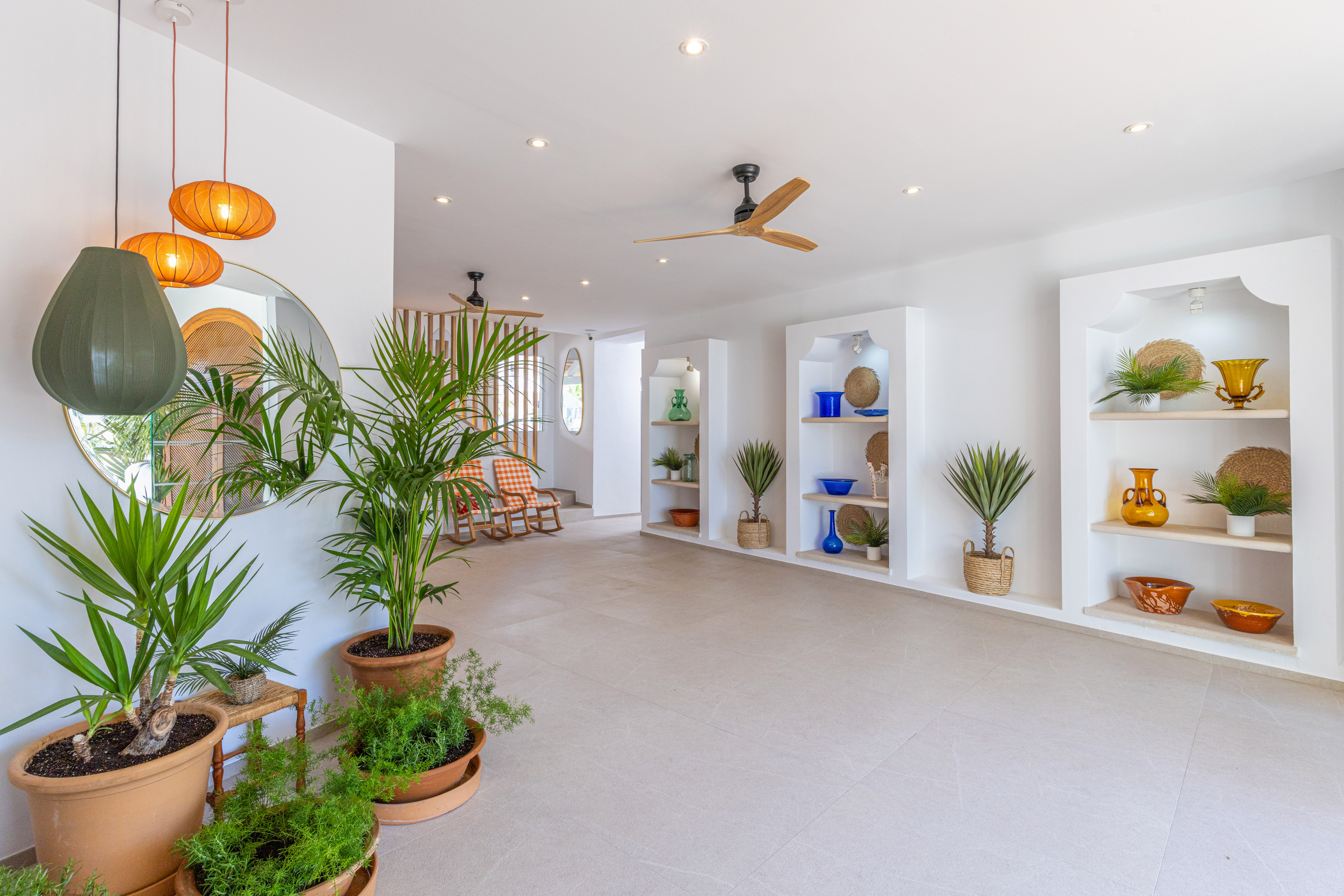 Bright Mediterranean lobby with potted plants, white walls, and elegant decor.