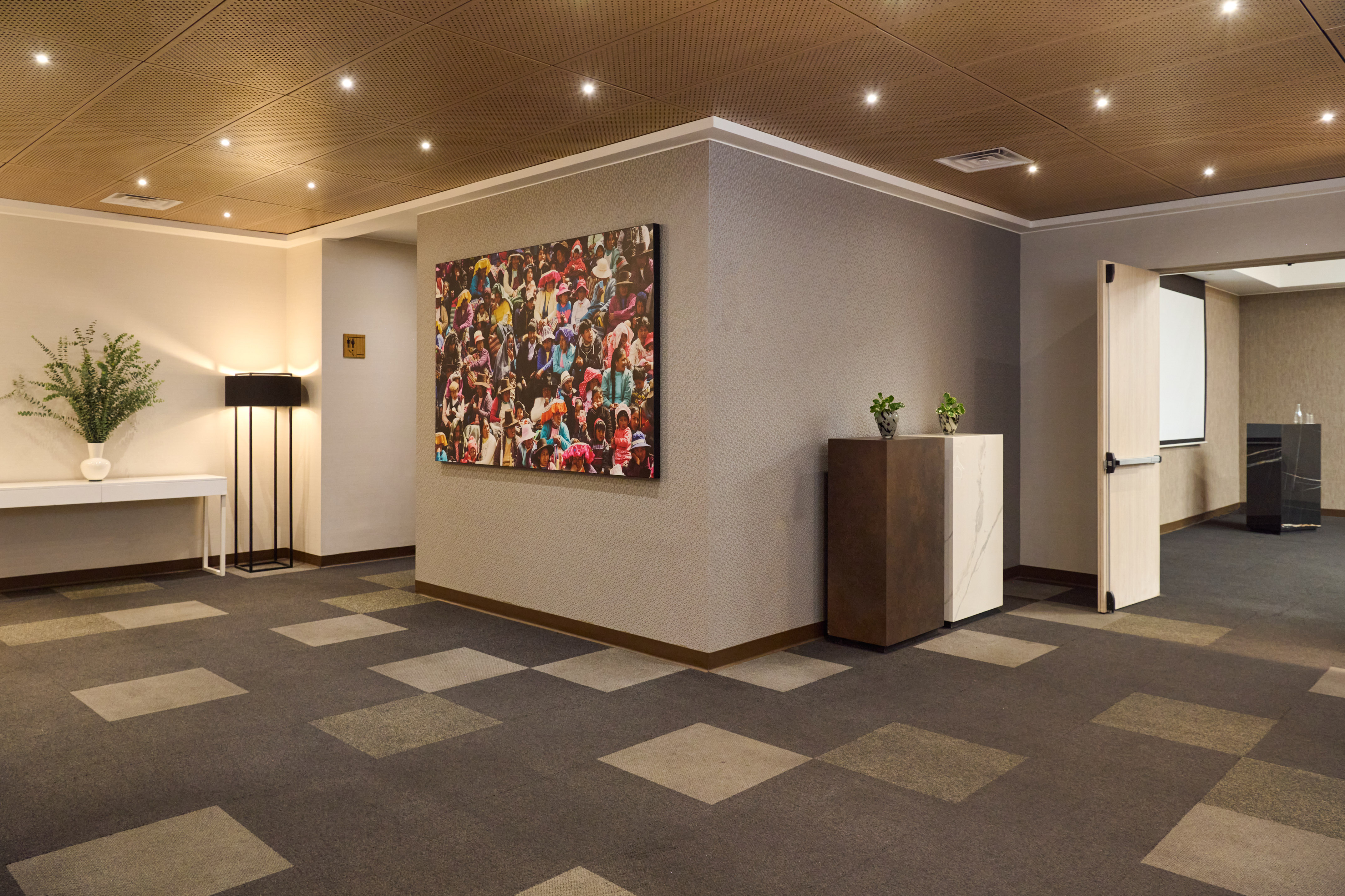 Modern conference hallway with vibrant art, patterned carpet, and ceiling lights.