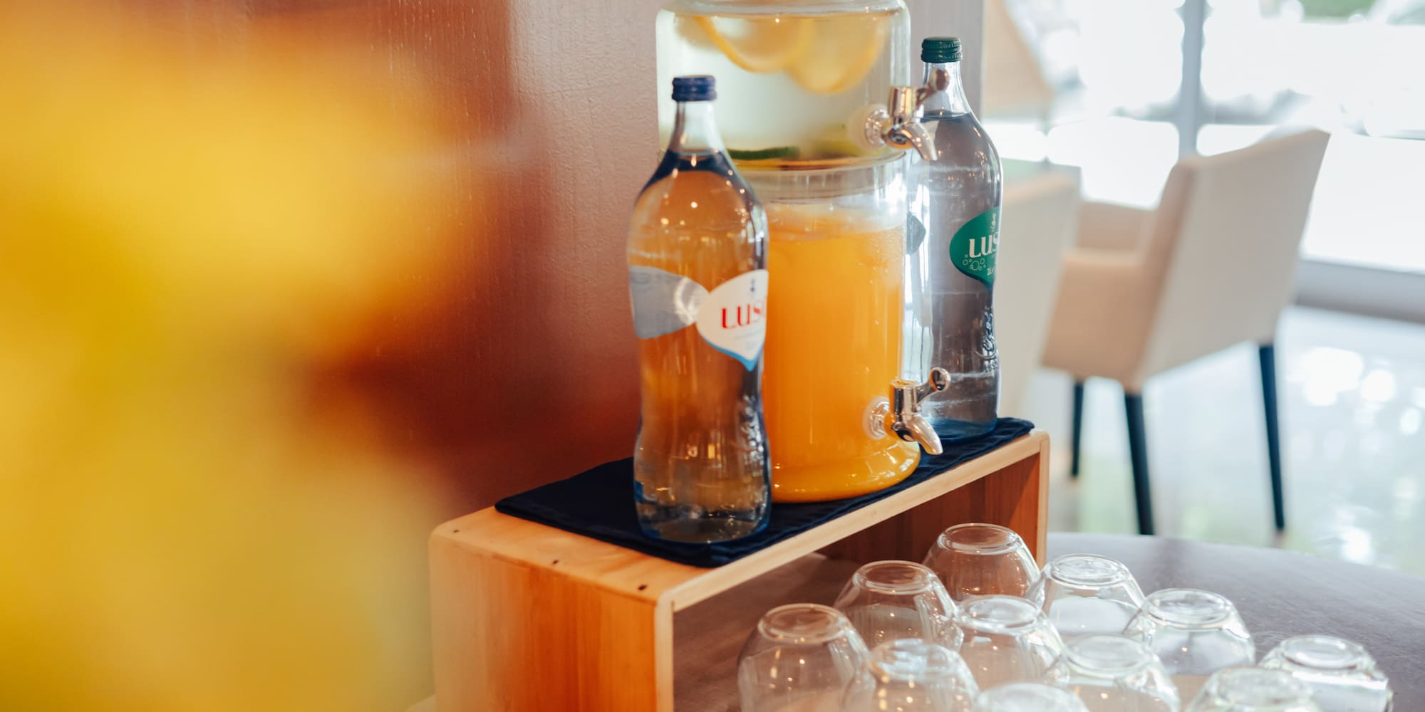 Refreshment station: lemon water, orange juice, bottled drinks, glasses.