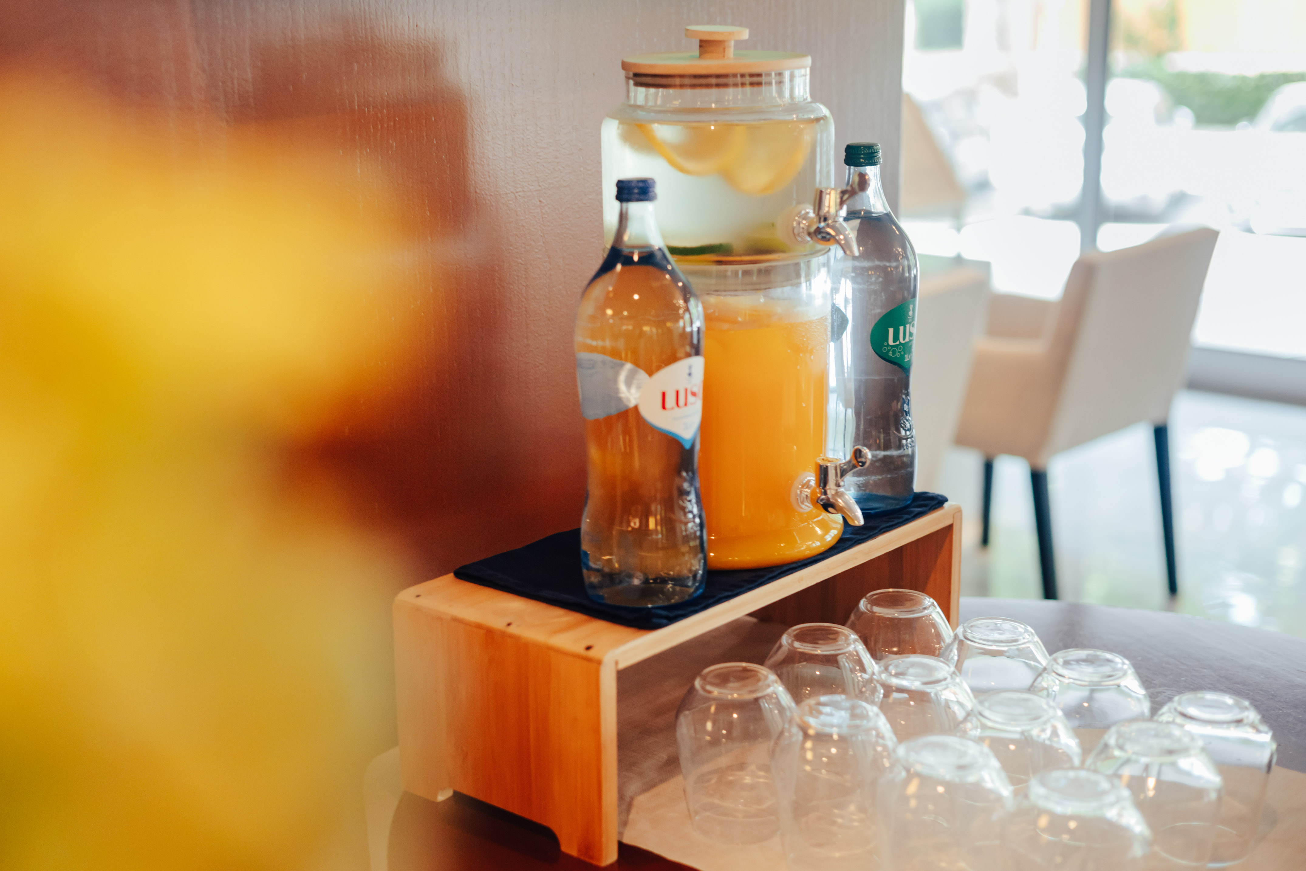 Refreshment station: lemon water, orange juice, bottled drinks, glasses.