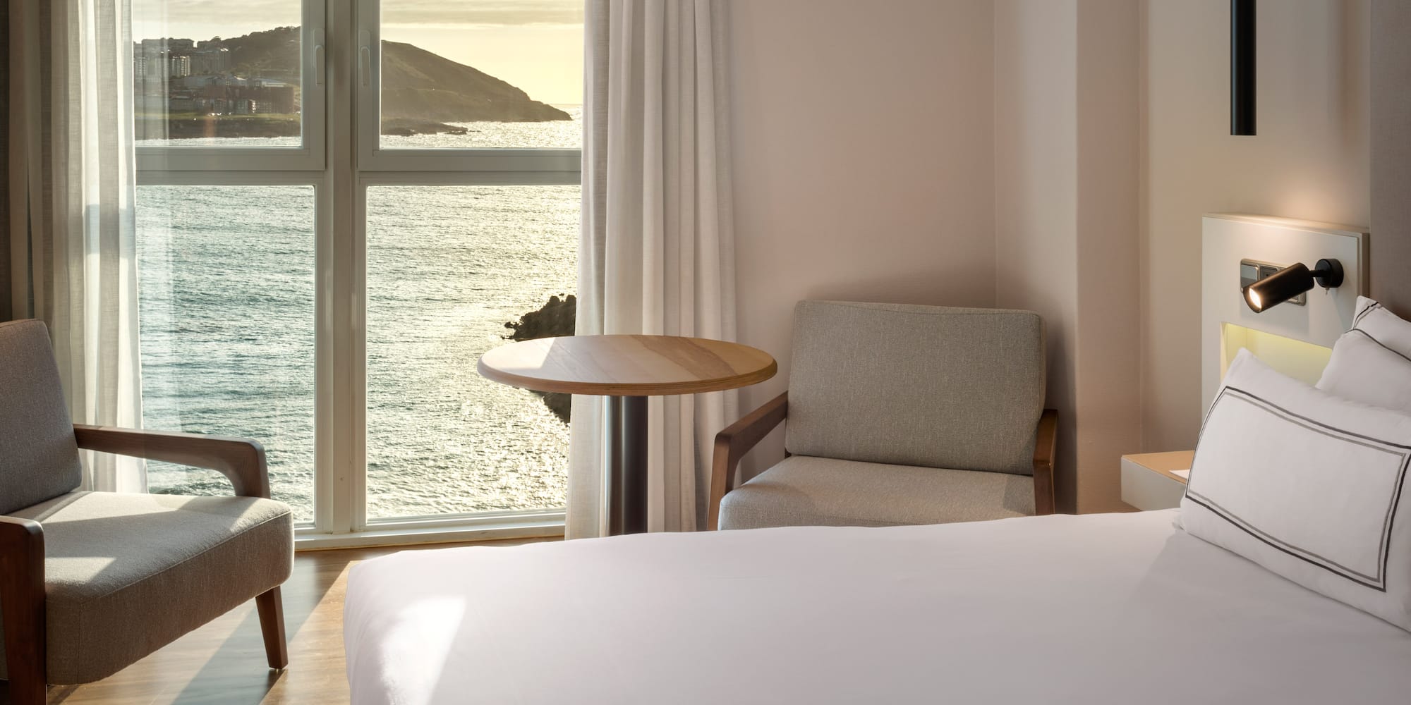 a room with a bed and chairs and a table and a window