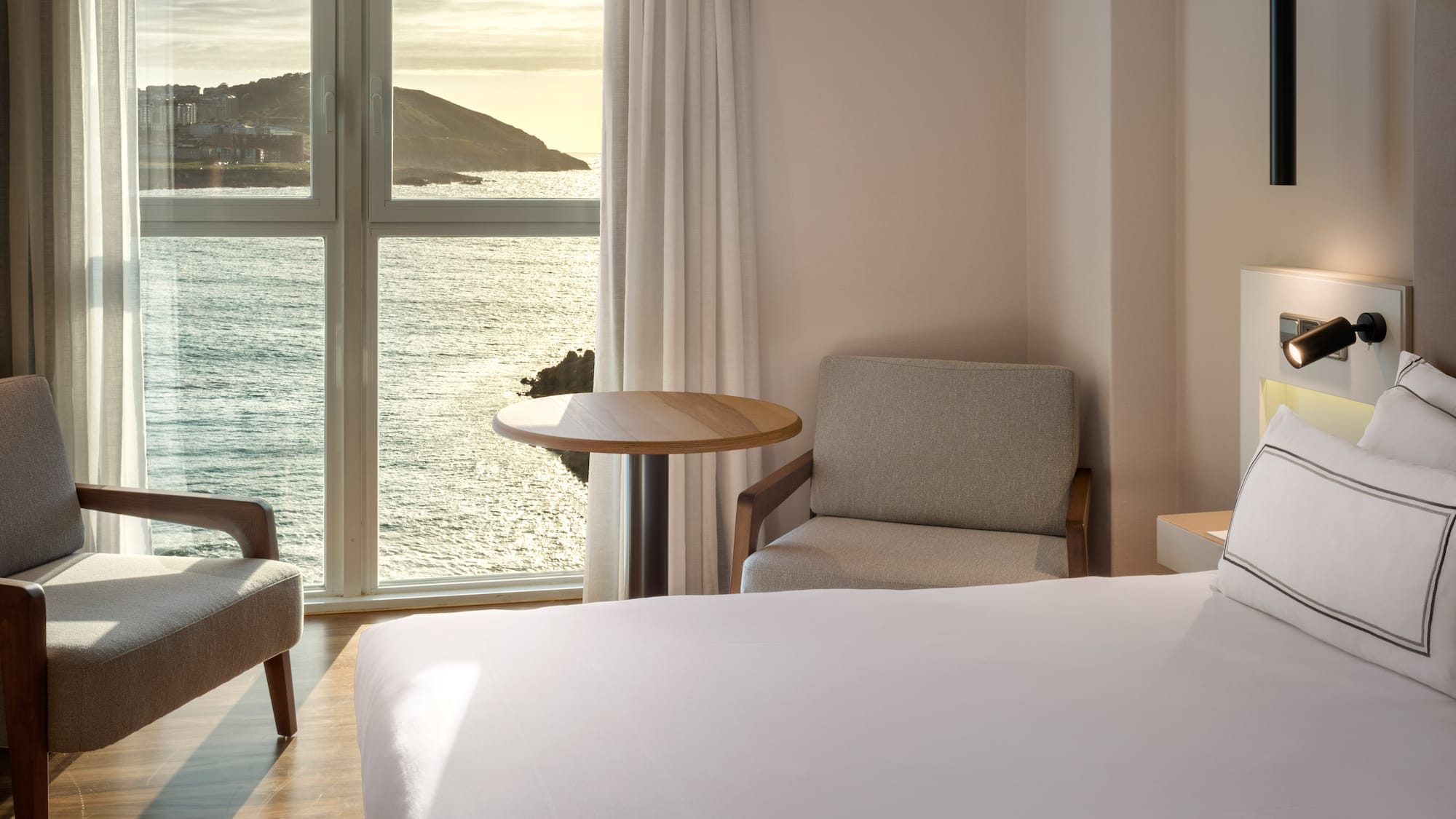 a room with a bed and chairs and a table and a window