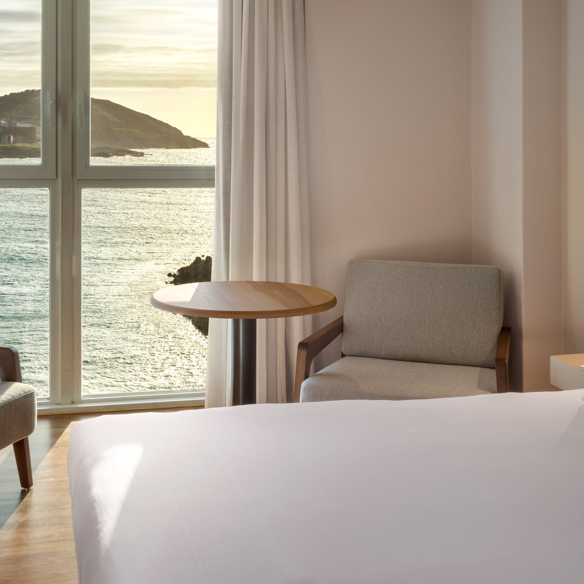 a room with a bed and chairs and a table and a window