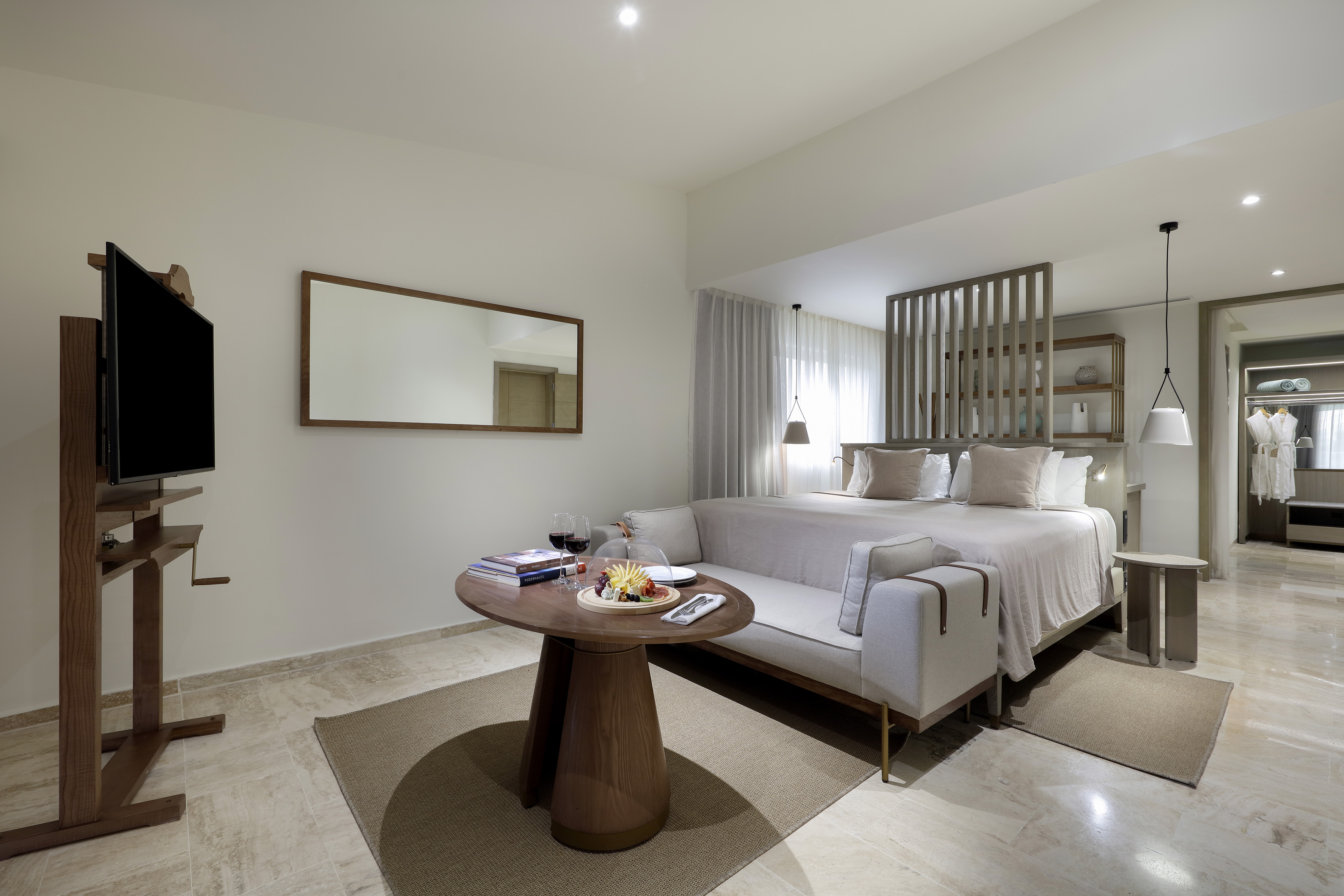 Luxury hotel suite with king bed, sofa, and coffee table with refreshments.