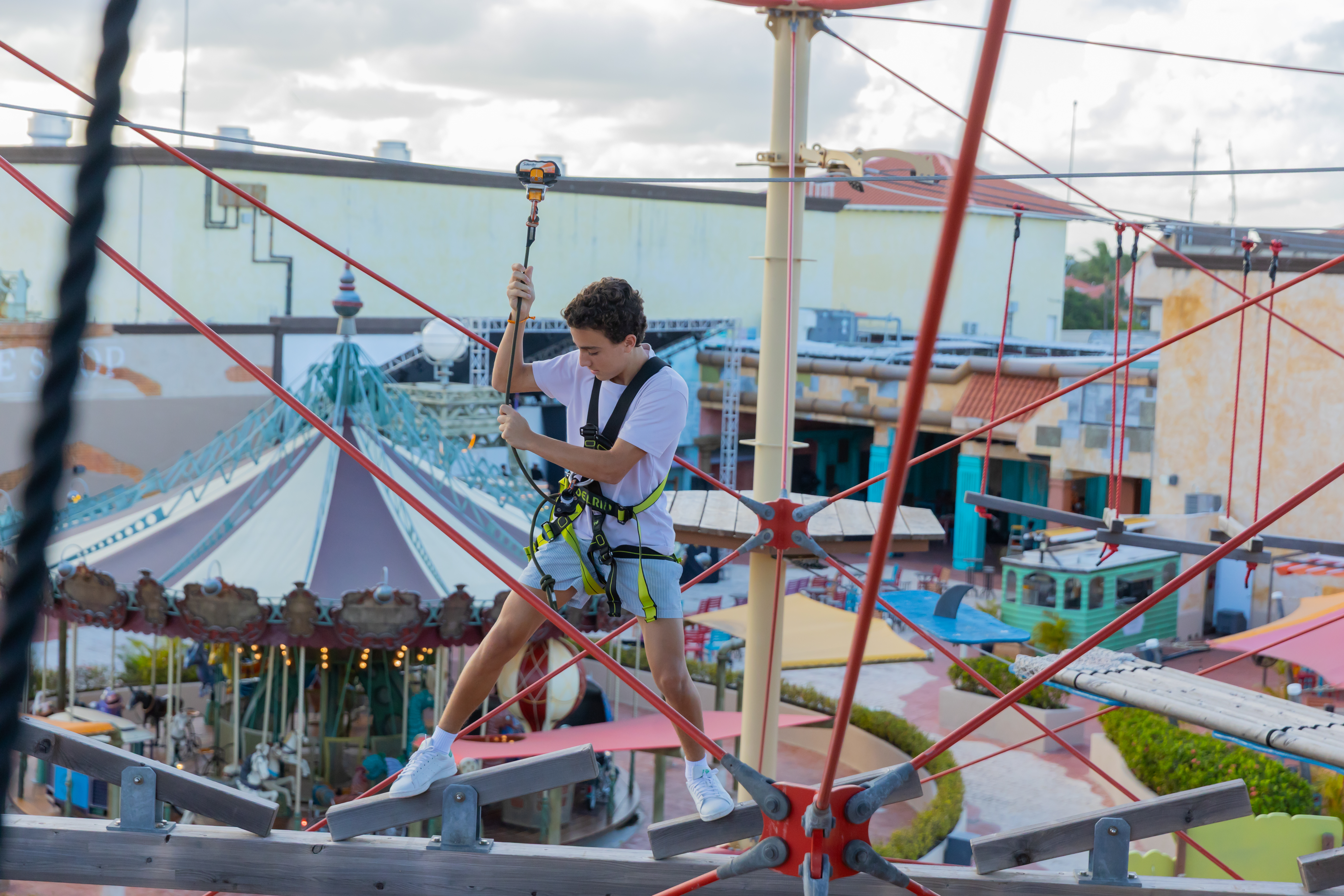 Young man navigating a high ropes course at an outdoor adventure park.