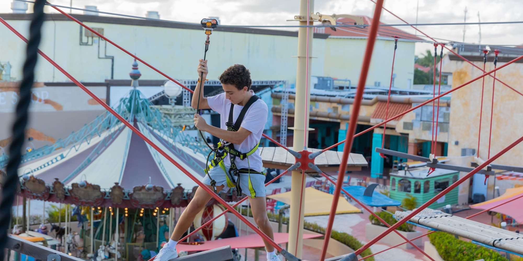 Young man navigating a high ropes course at an outdoor adventure park.