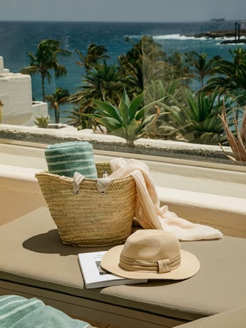 a hat and a basket on a bench outside by a window