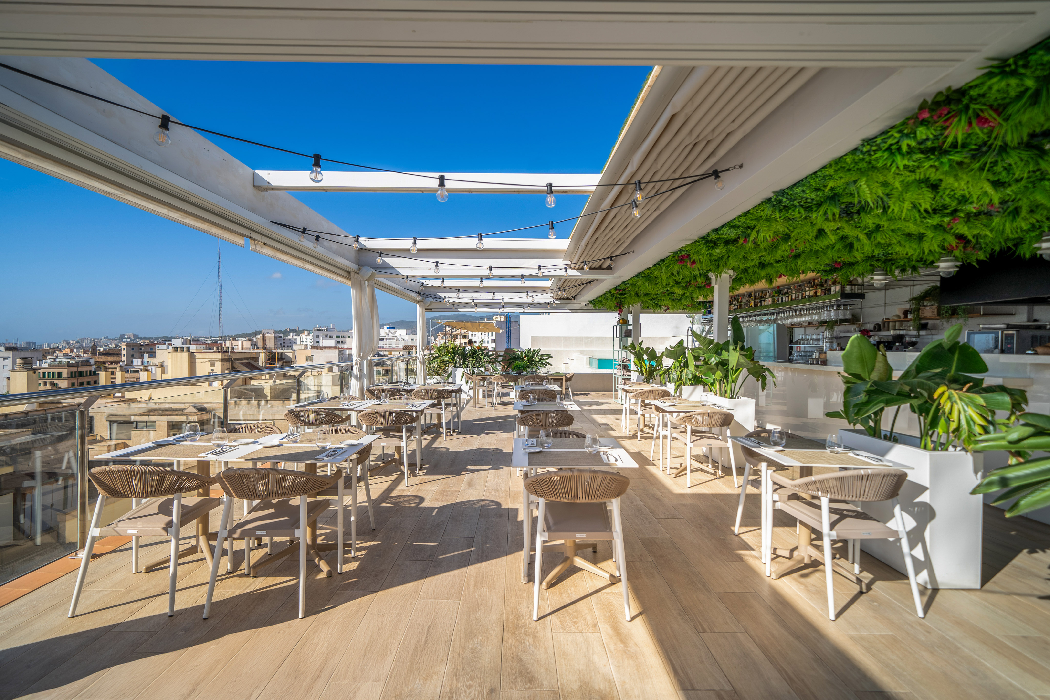 Rooftop restaurant terrace, outdoor dining with city view and string lights.