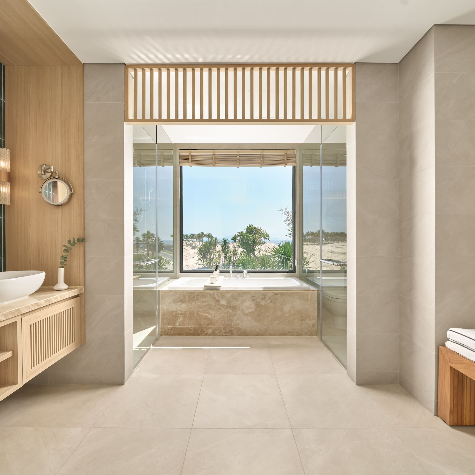 Modern luxury bathroom with soaking tub and panoramic tropical view.