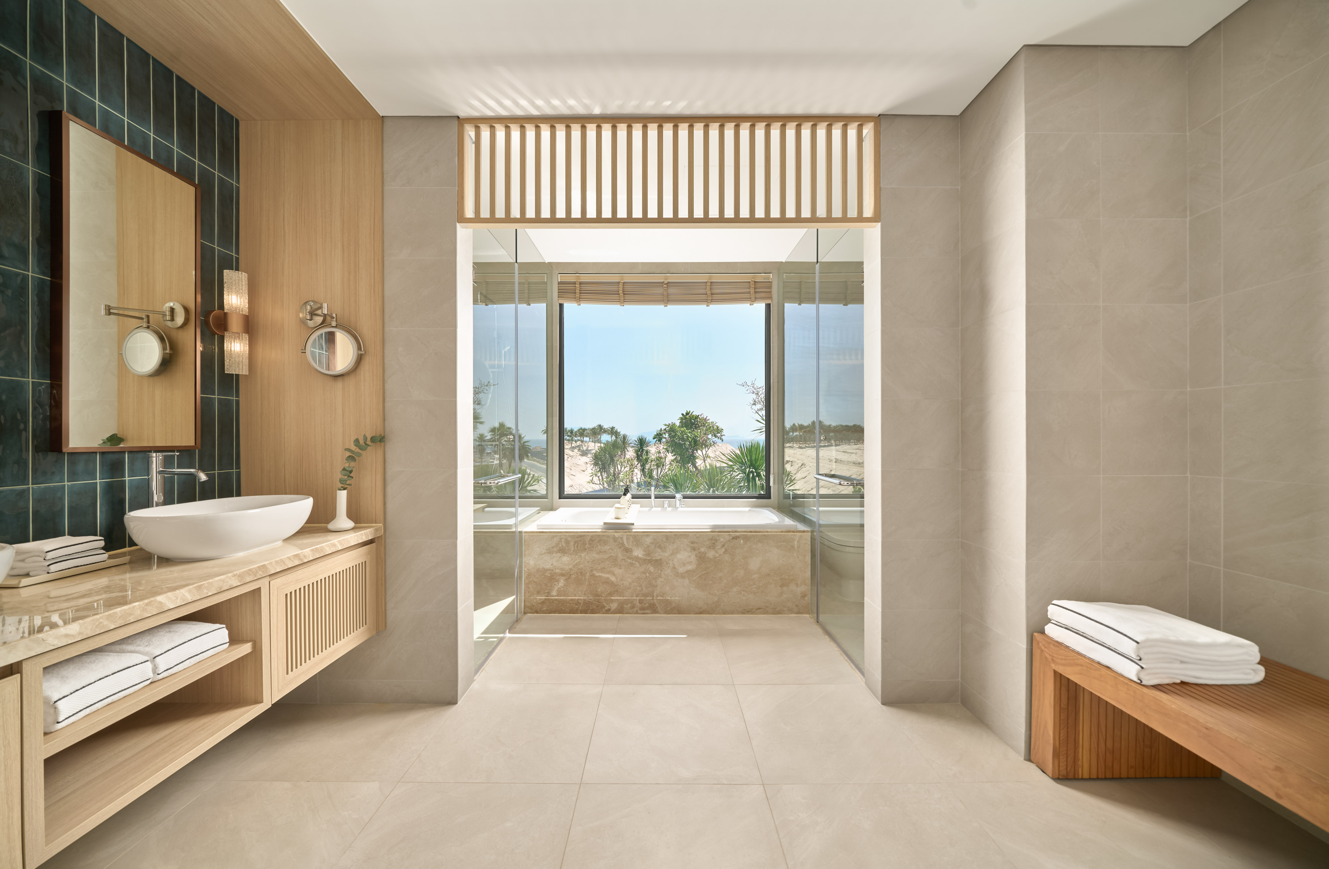 Modern luxury bathroom with soaking tub and panoramic tropical view.