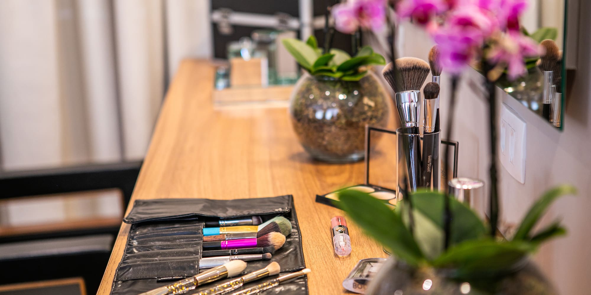 a table with makeup brushes and flowers