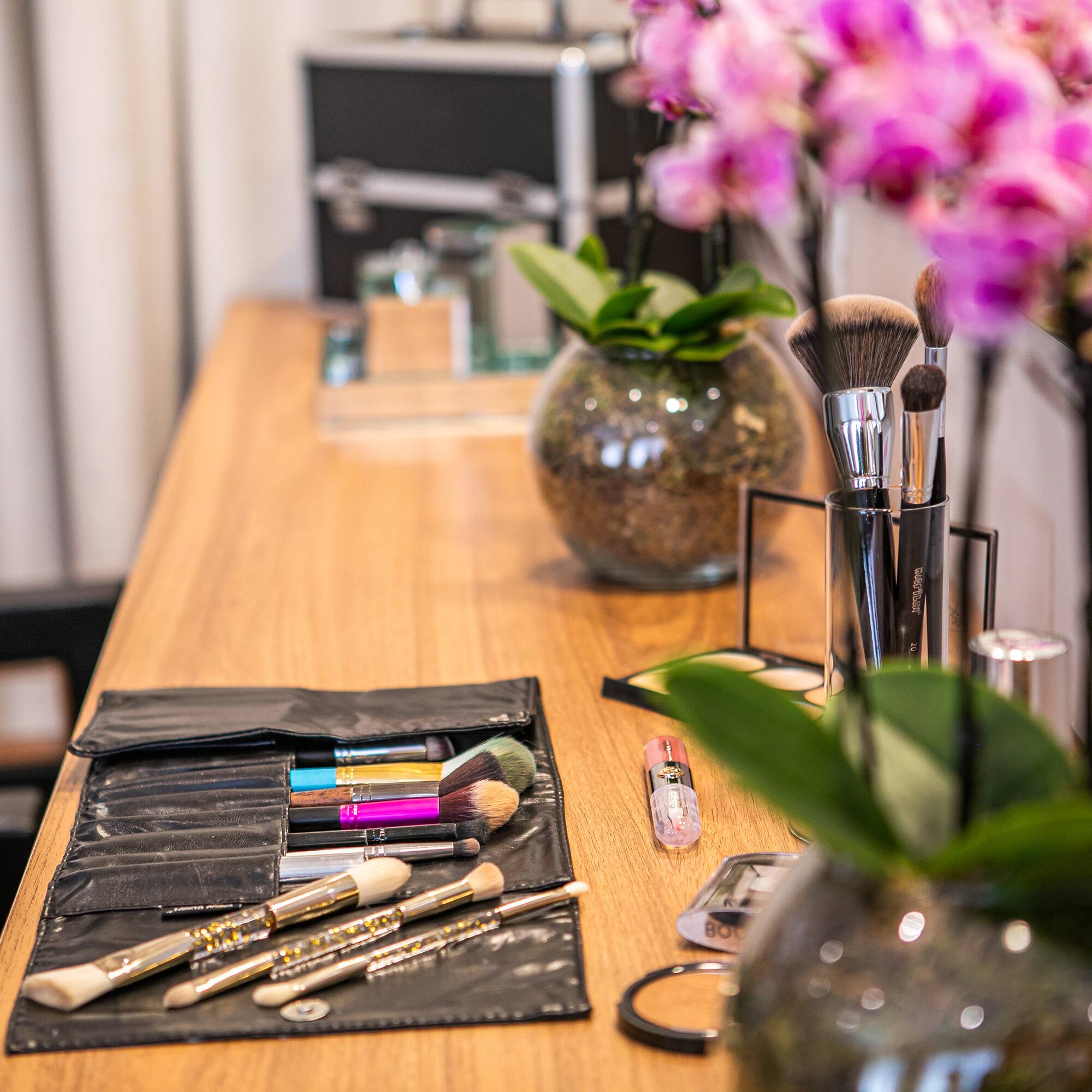 a table with makeup brushes and flowers