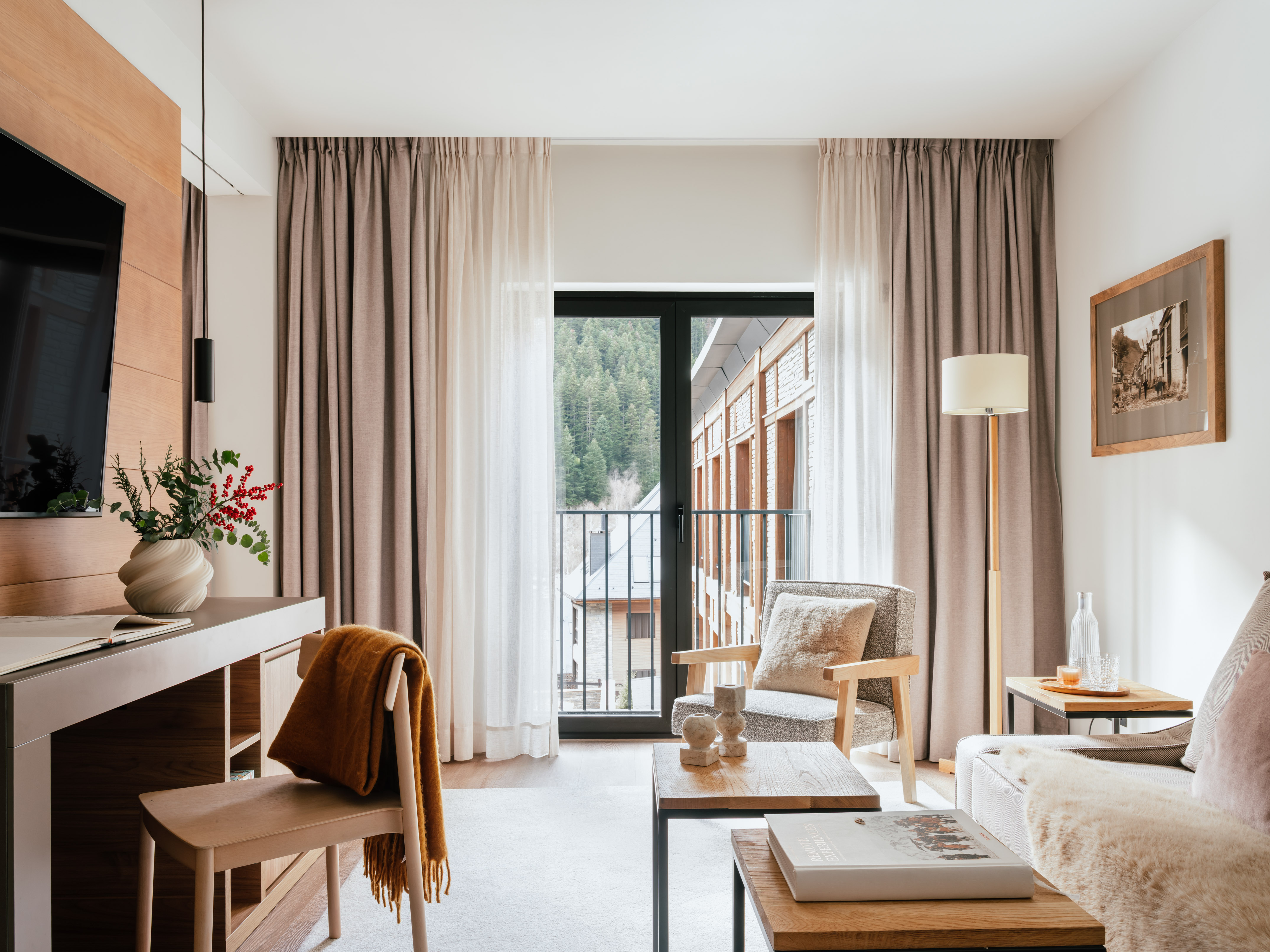 Cozy hotel suite living area with mountain view balcony, modern decor.