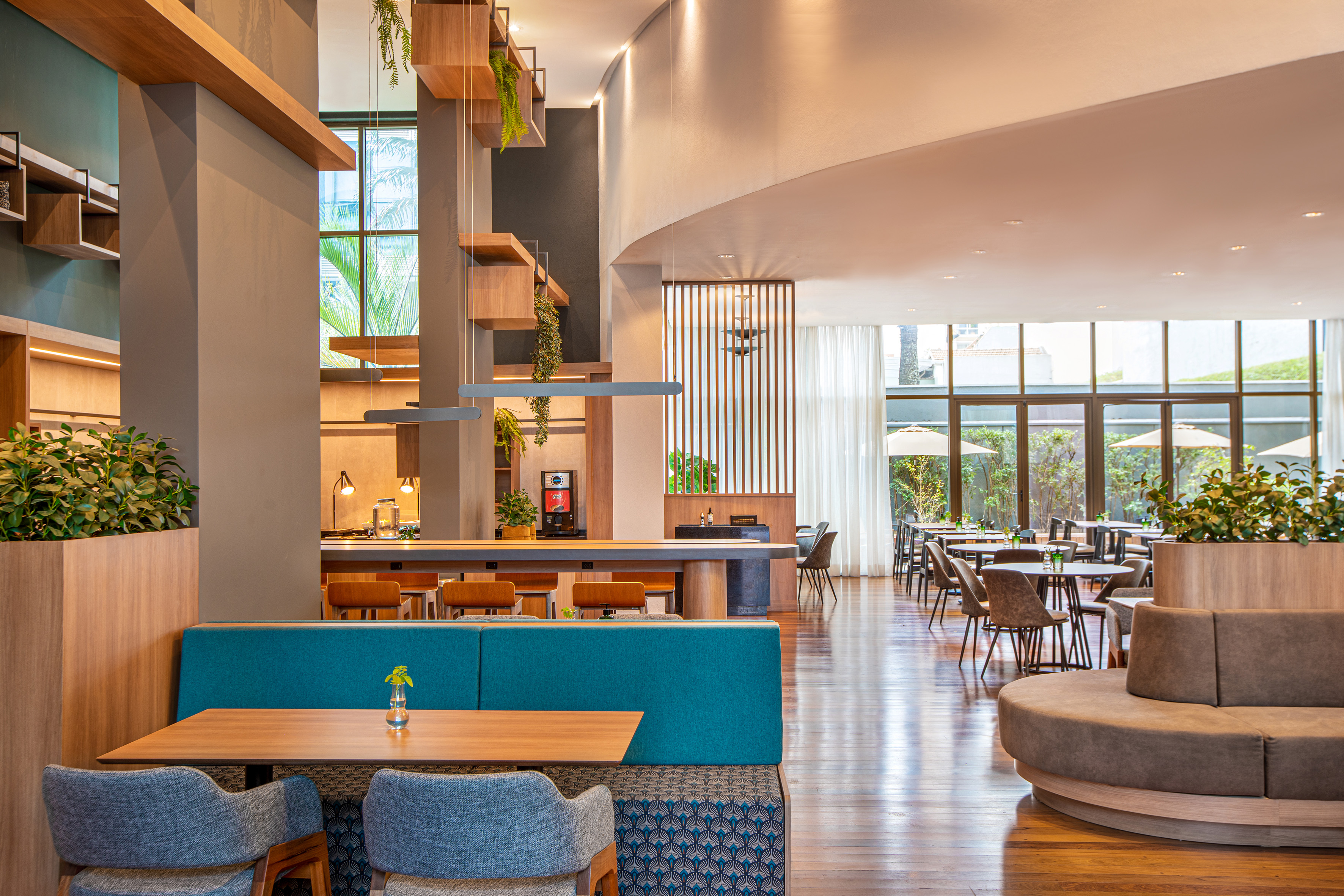 Contemporary restaurant interior featuring teal banquettes and natural light.