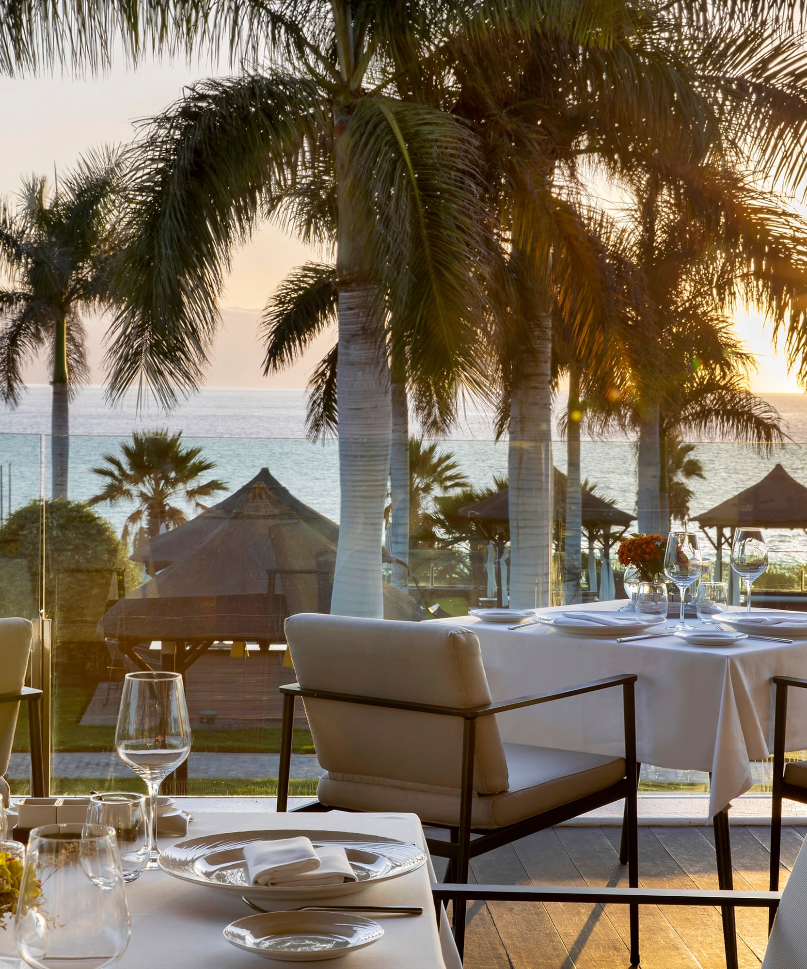 a table set for a dinner with palm trees and a beach in the background