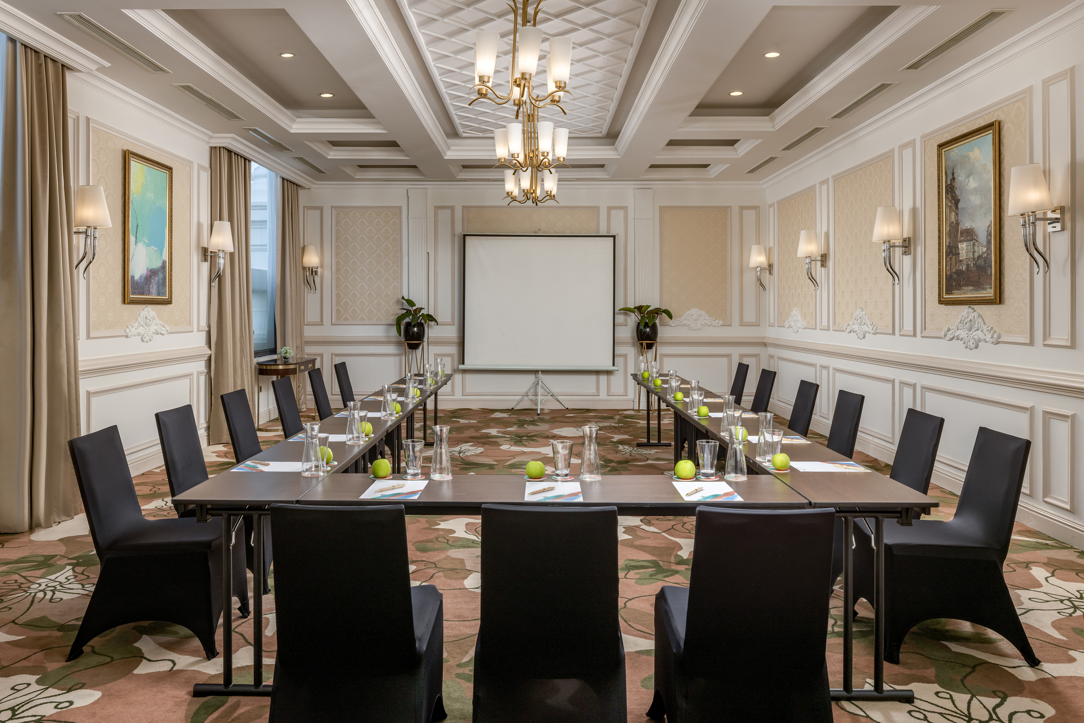 Elegant U-shaped conference room with presentation screen, luxurious decor.