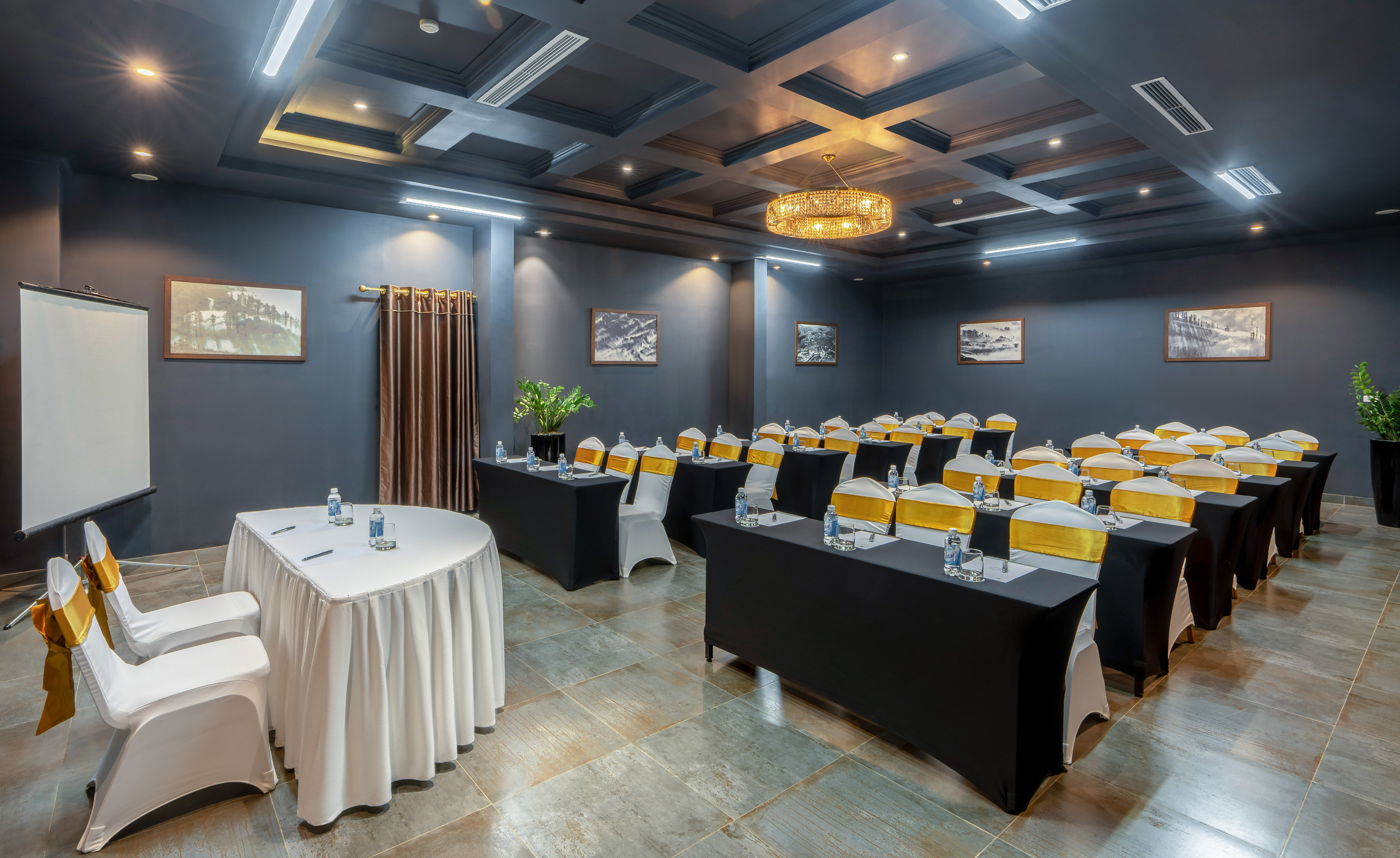 Modern conference room, black tables, gold-sash chairs, projector screen.