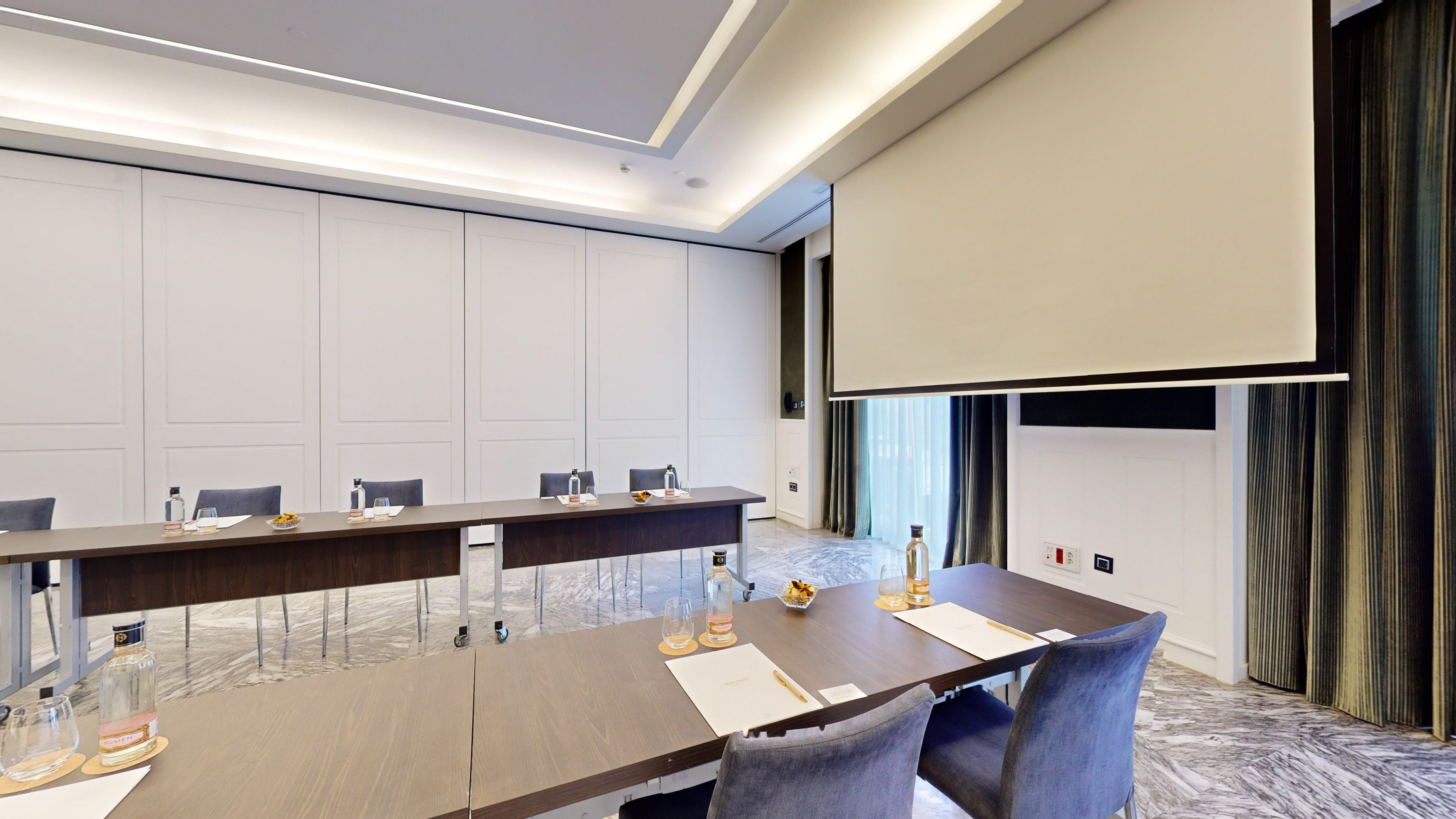 Modern conference room with tables, chairs, and a projector screen.