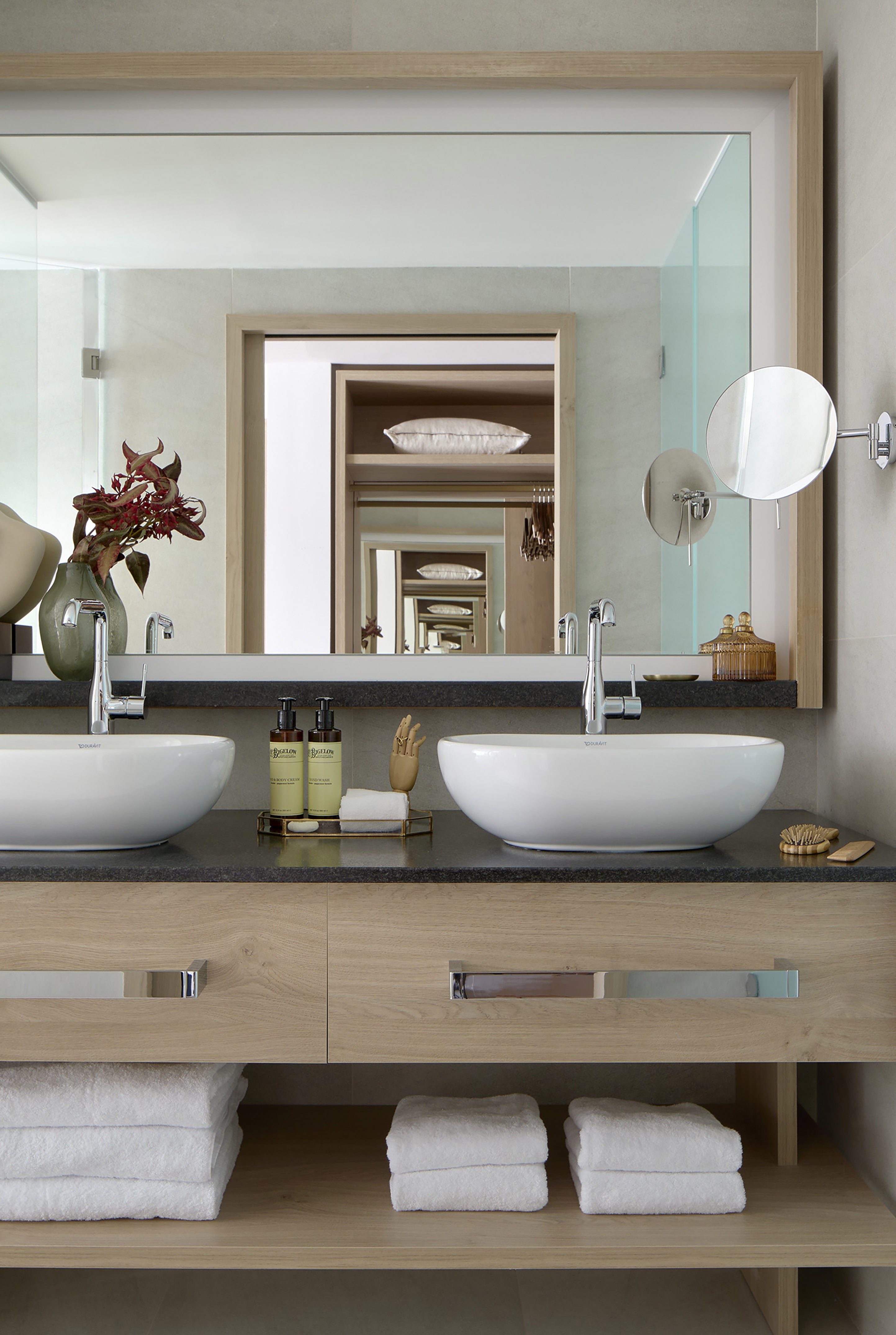 Modern double vanity bathroom with vessel sinks, wood cabinet, and large mirror.
