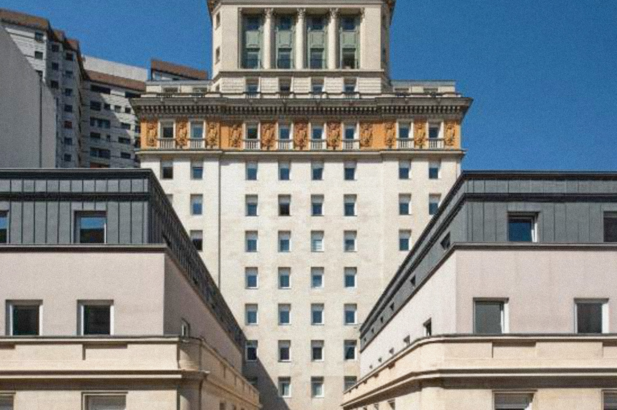Ornate classical building with tiered tower, framed by urban architecture.