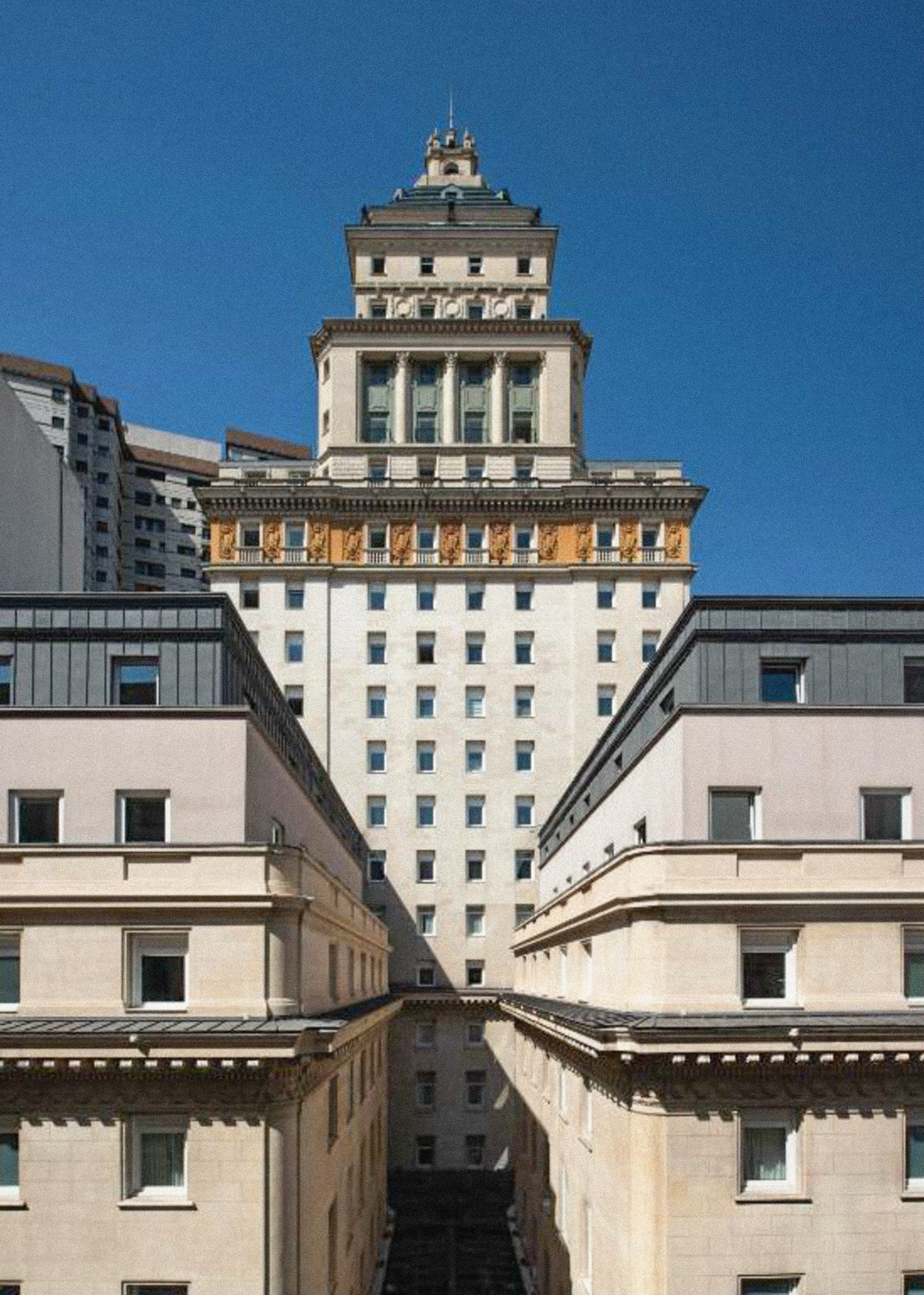 Ornate classical building with tiered tower, framed by urban architecture.