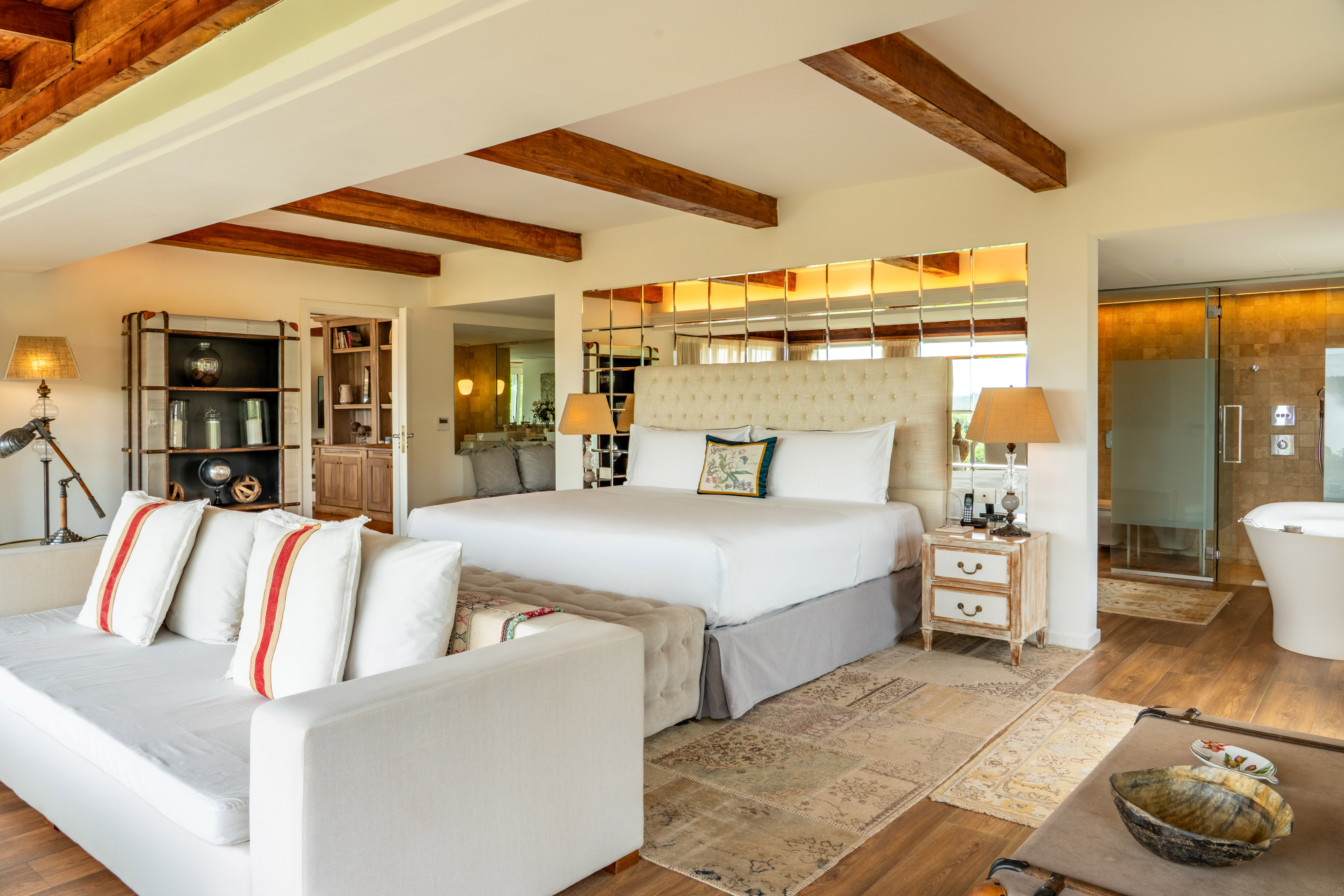 Luxury master bedroom suite with king bed, wood beams, and spa-style bathroom.